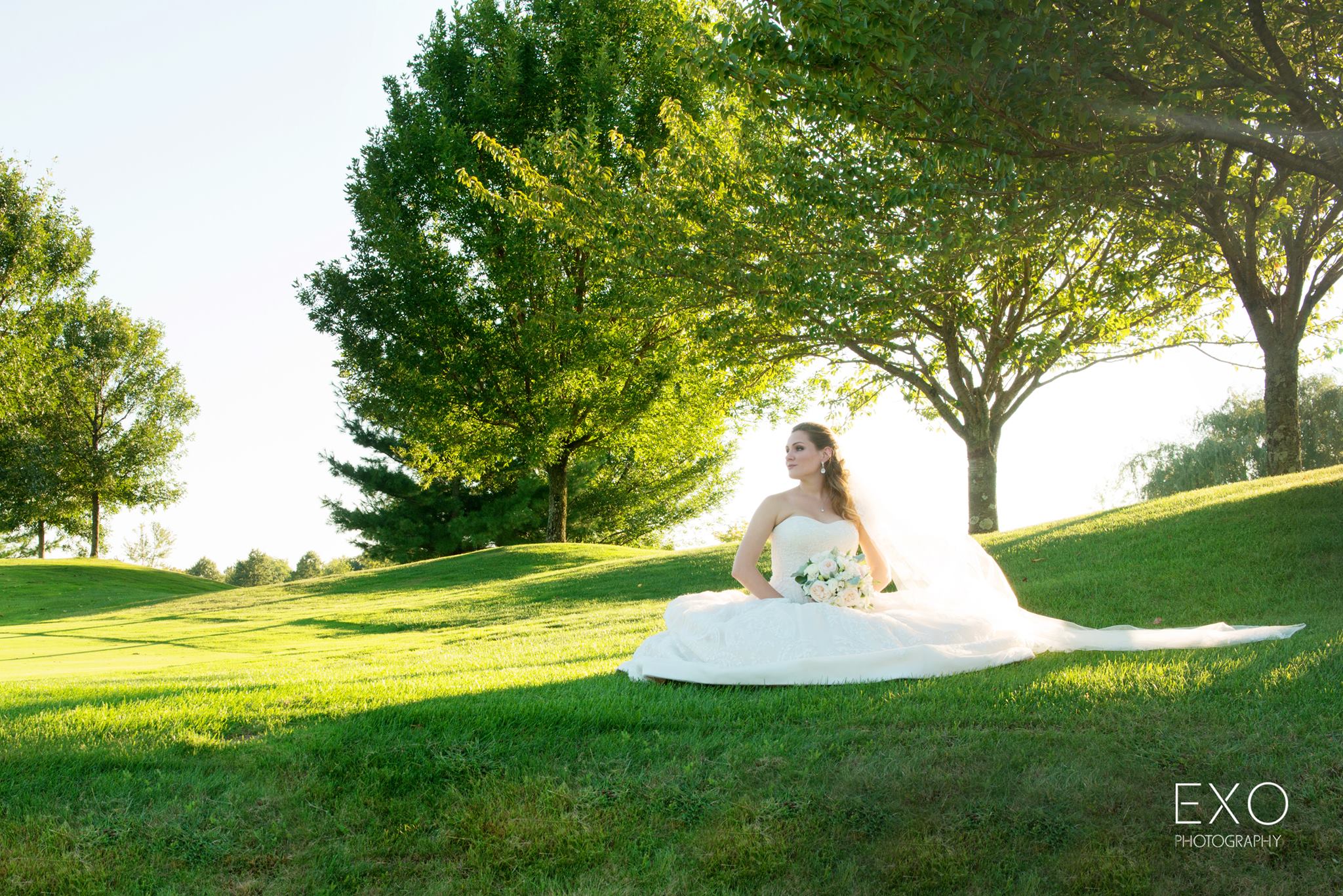 bride sitting on green grass at Willow Creek Golf and Country Club