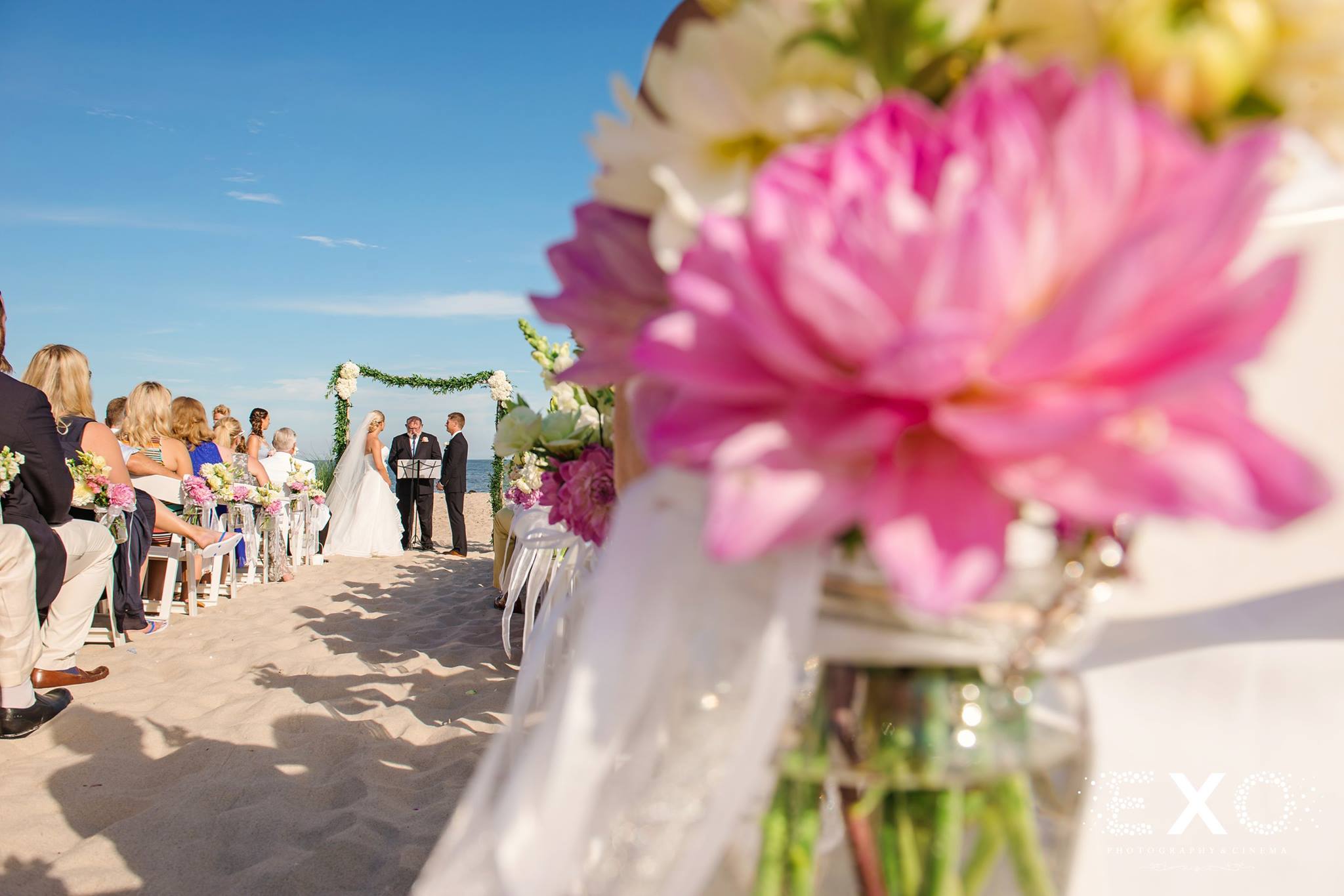 perspective shot of bride and groom at the end of the aisle with flowers by rori flower decor