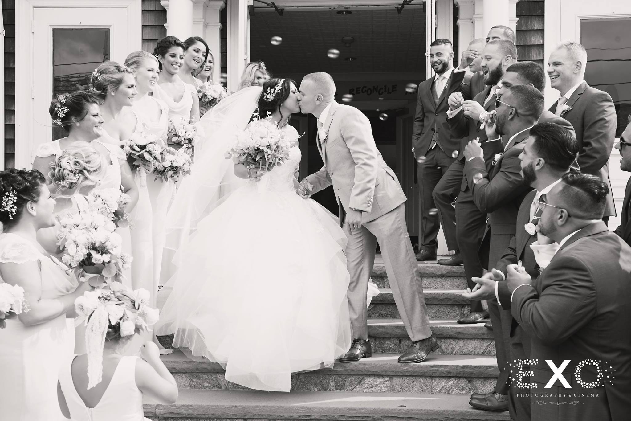 black and white photo of bride and groom kissing on stairs