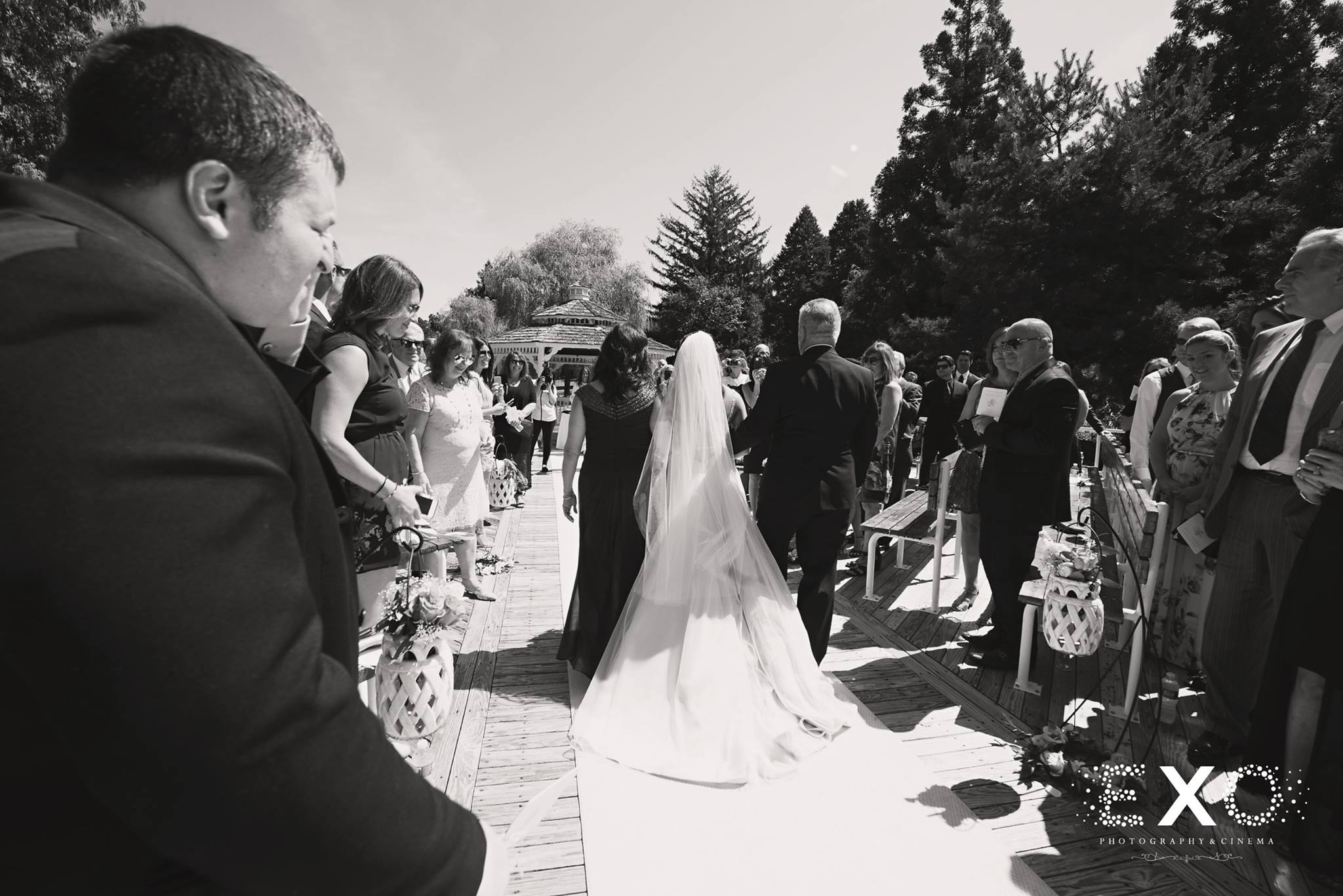 black and white image of parents walking bride down the aisle 