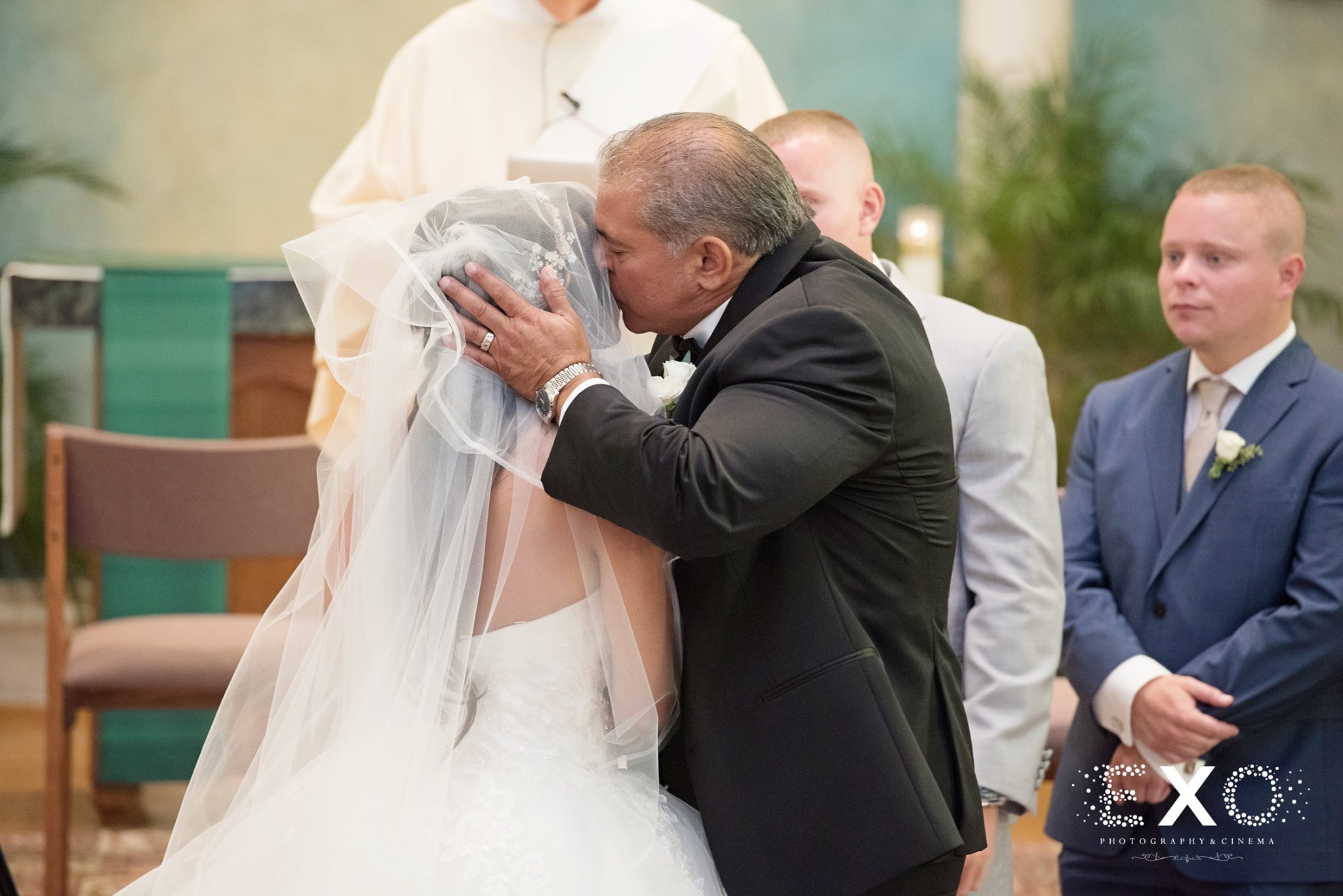 father kissing bride at ceremony