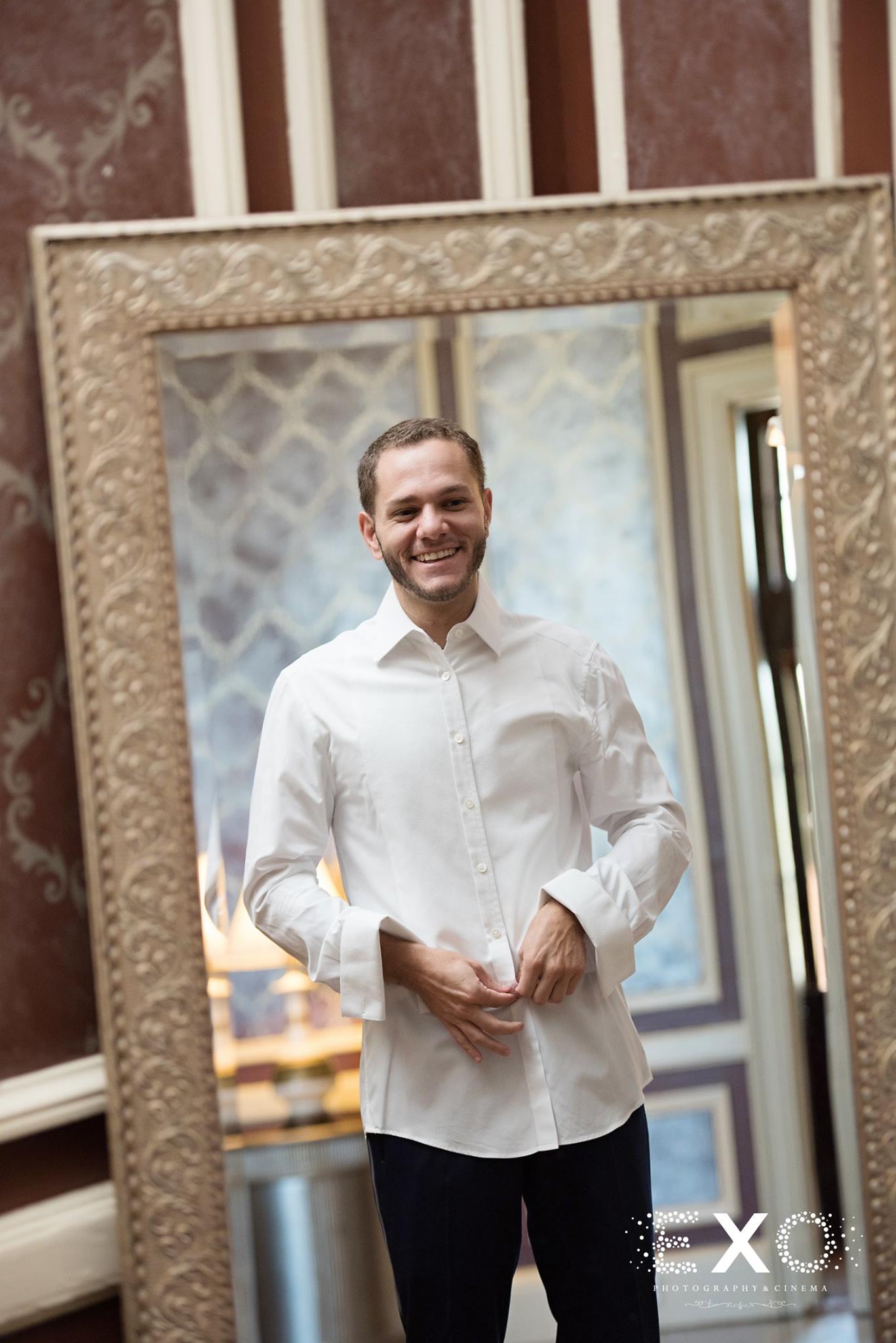 groom smiling and buttoning shirt