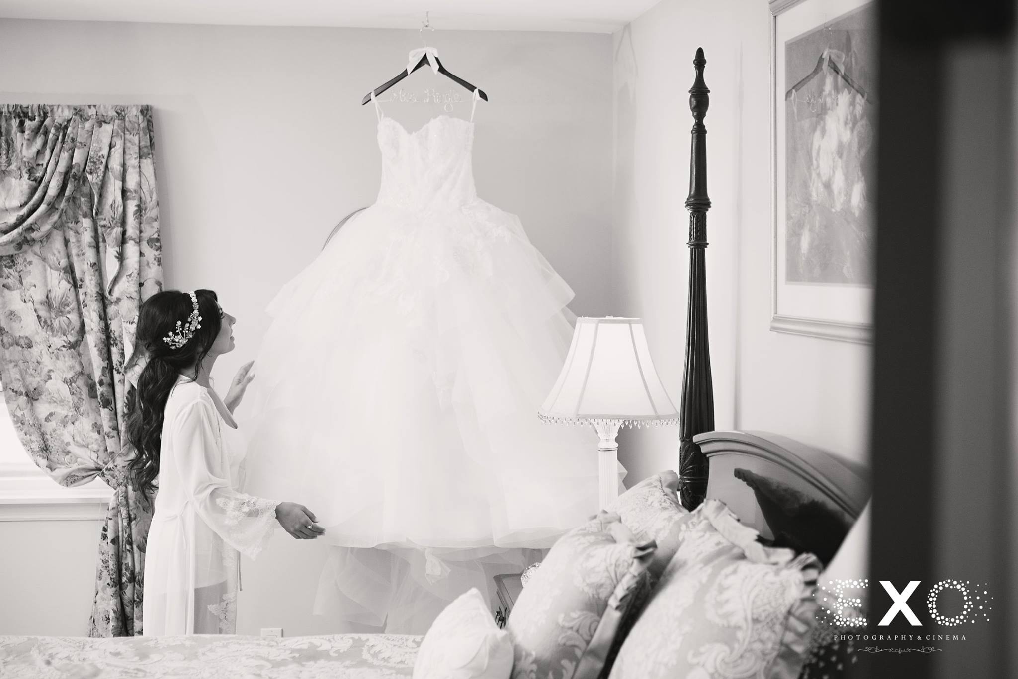black and white picture of bride with bridal gown from wedding salon of manhasset hanging from ceiling 