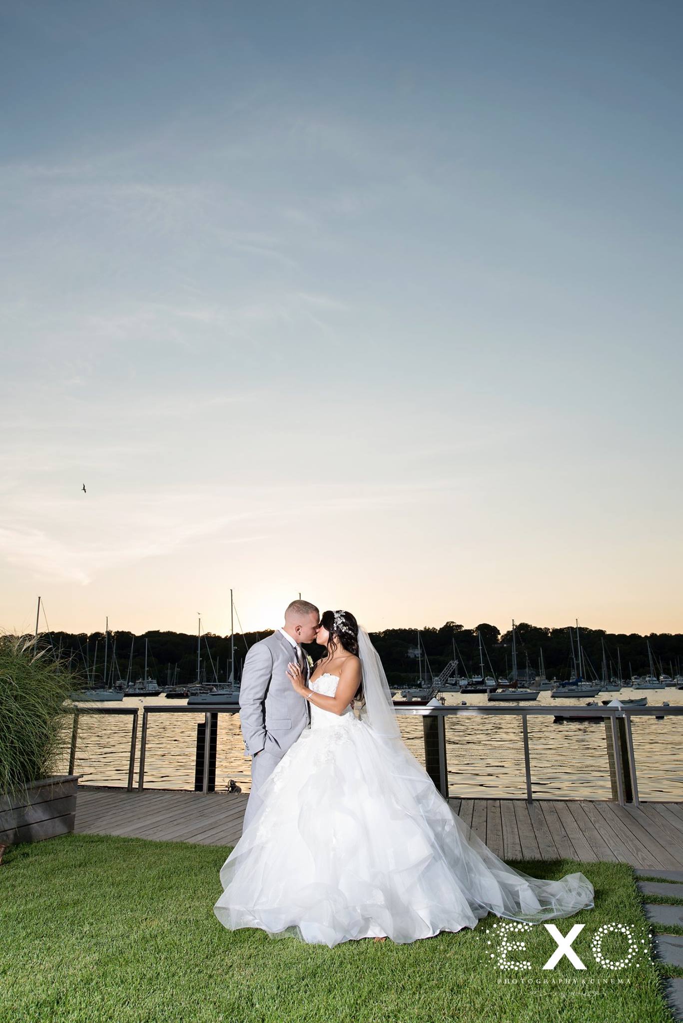 bride and groom kissing with sunset by water