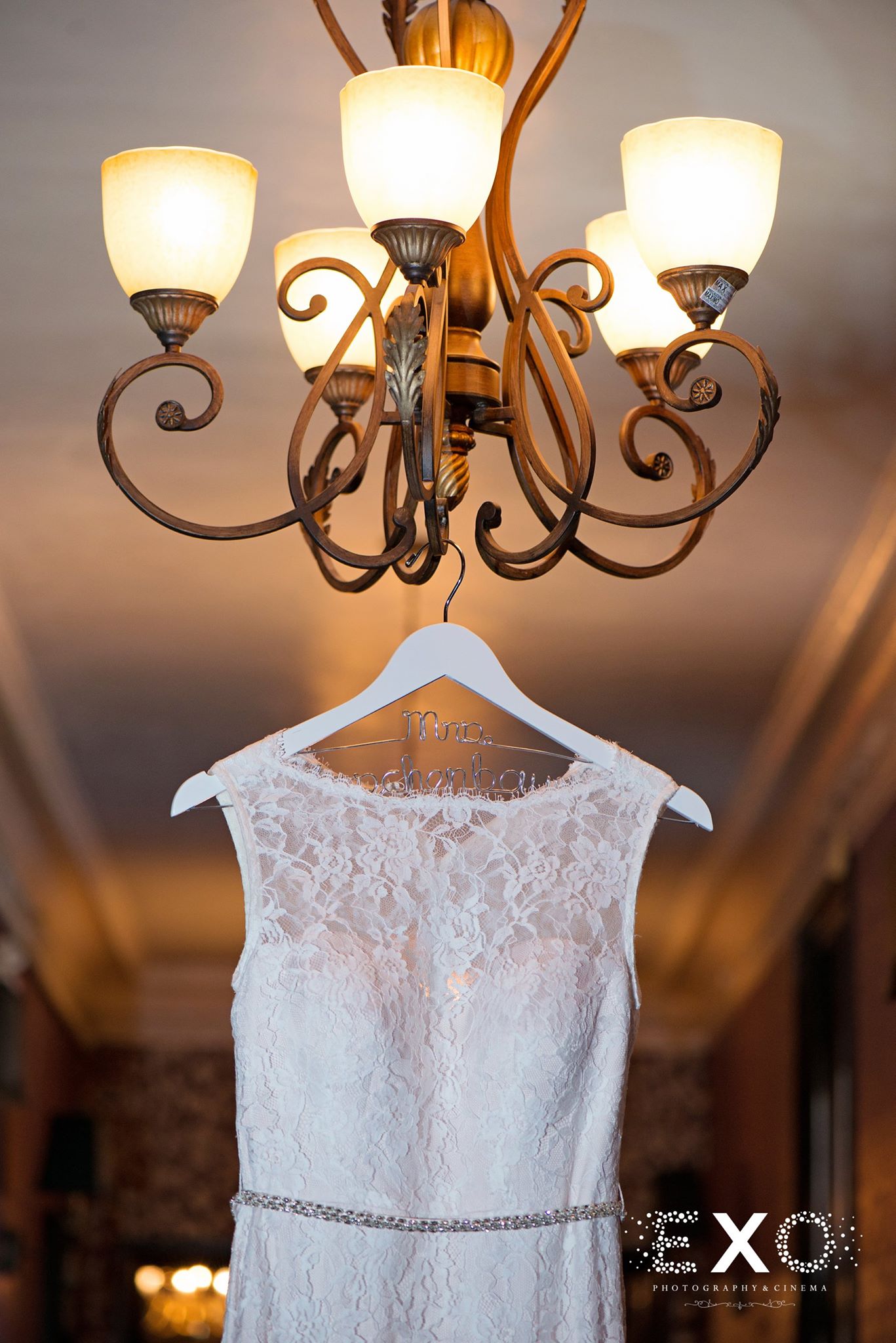 bridal gown and custom made hanger hanging from light fixture