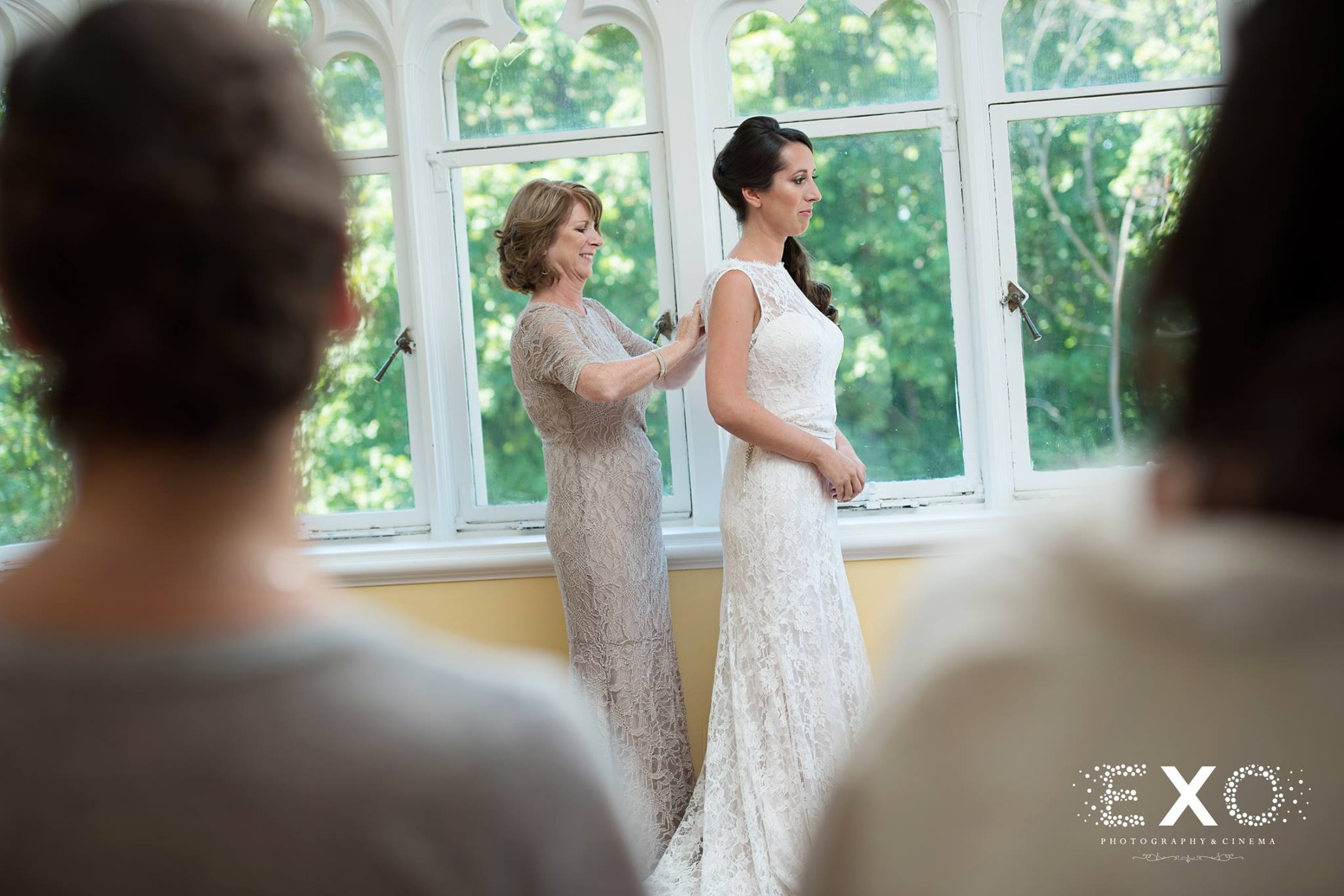 bride and mother adjusting gown by window