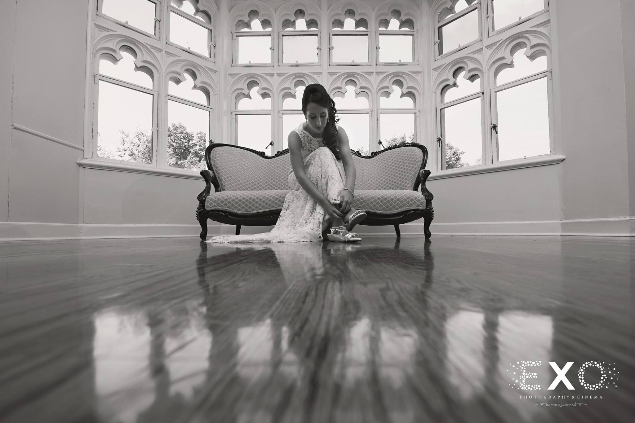 black and white image of bride fixing shoes