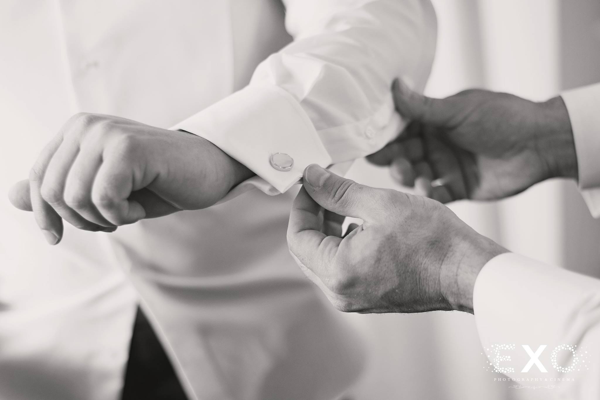 black and white image of groom fixing shirt 
