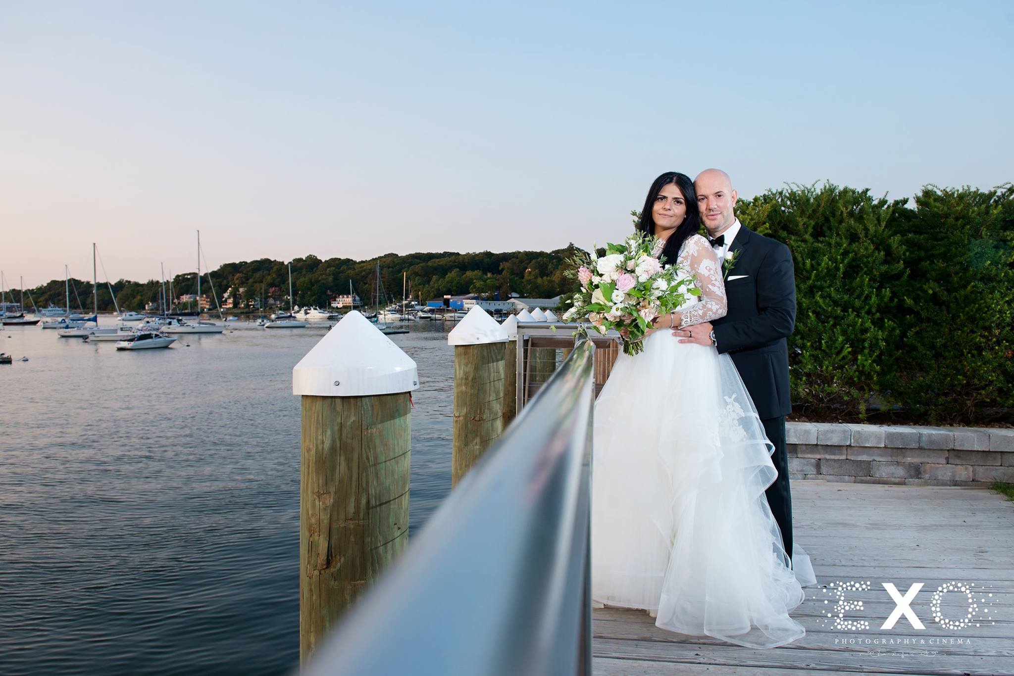 bride and groom on rail by water at the Harbor Club at Prime
