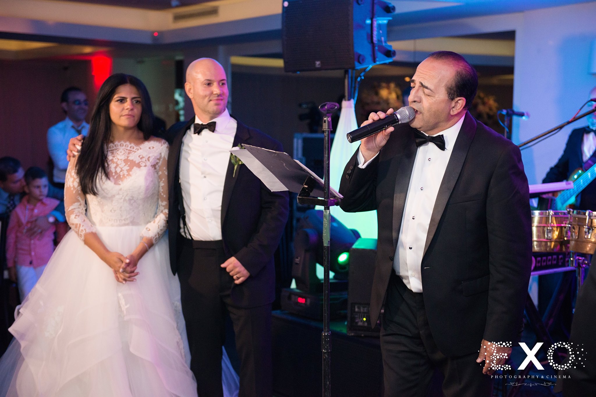 bride and groom standing on stage by singer