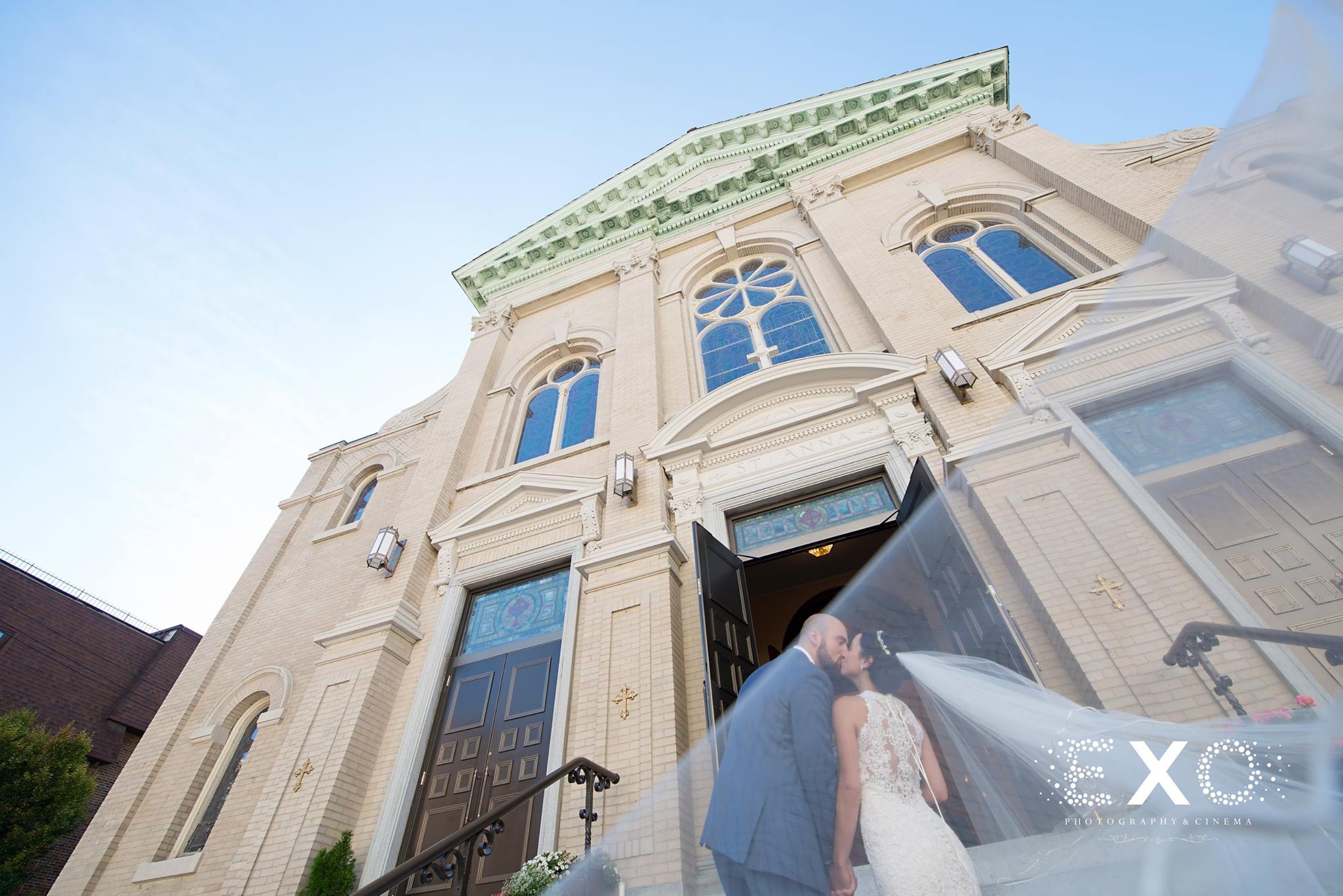 low perspective shot of bride and groom under veil by st anna church