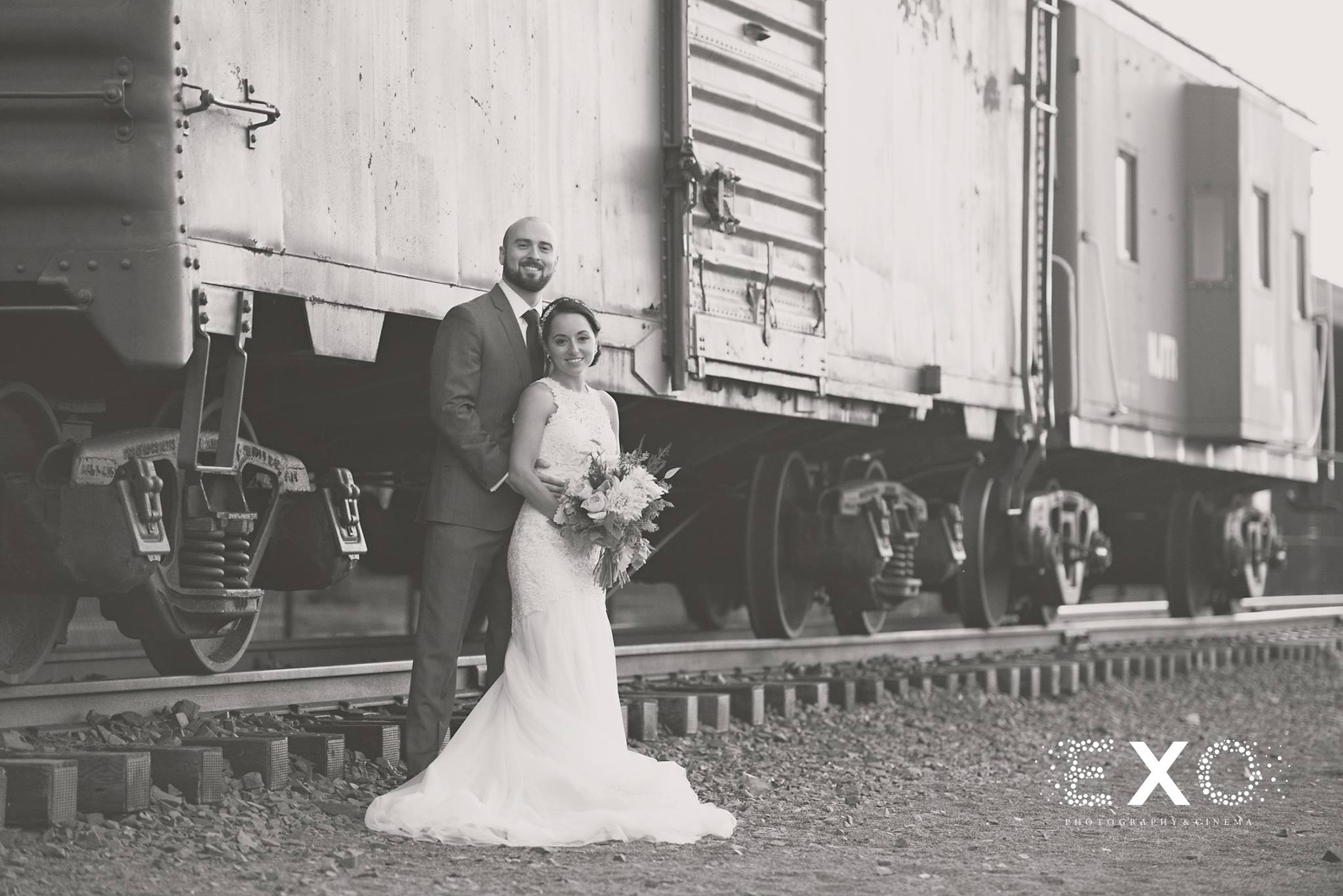 black and white image of bride and groom by train car