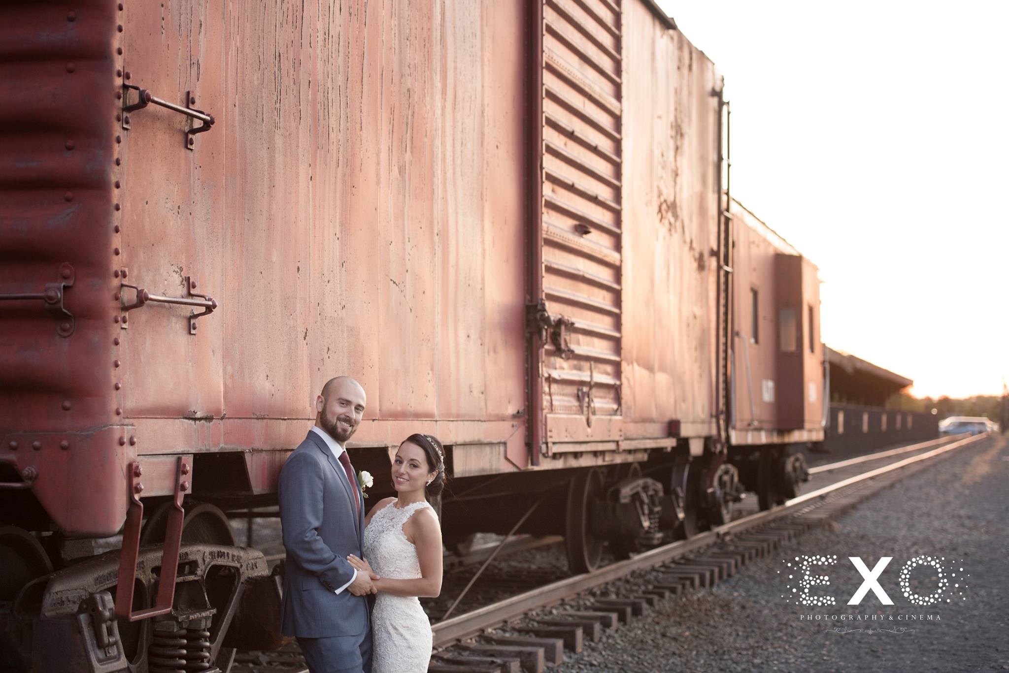 bride and groom standing by train car