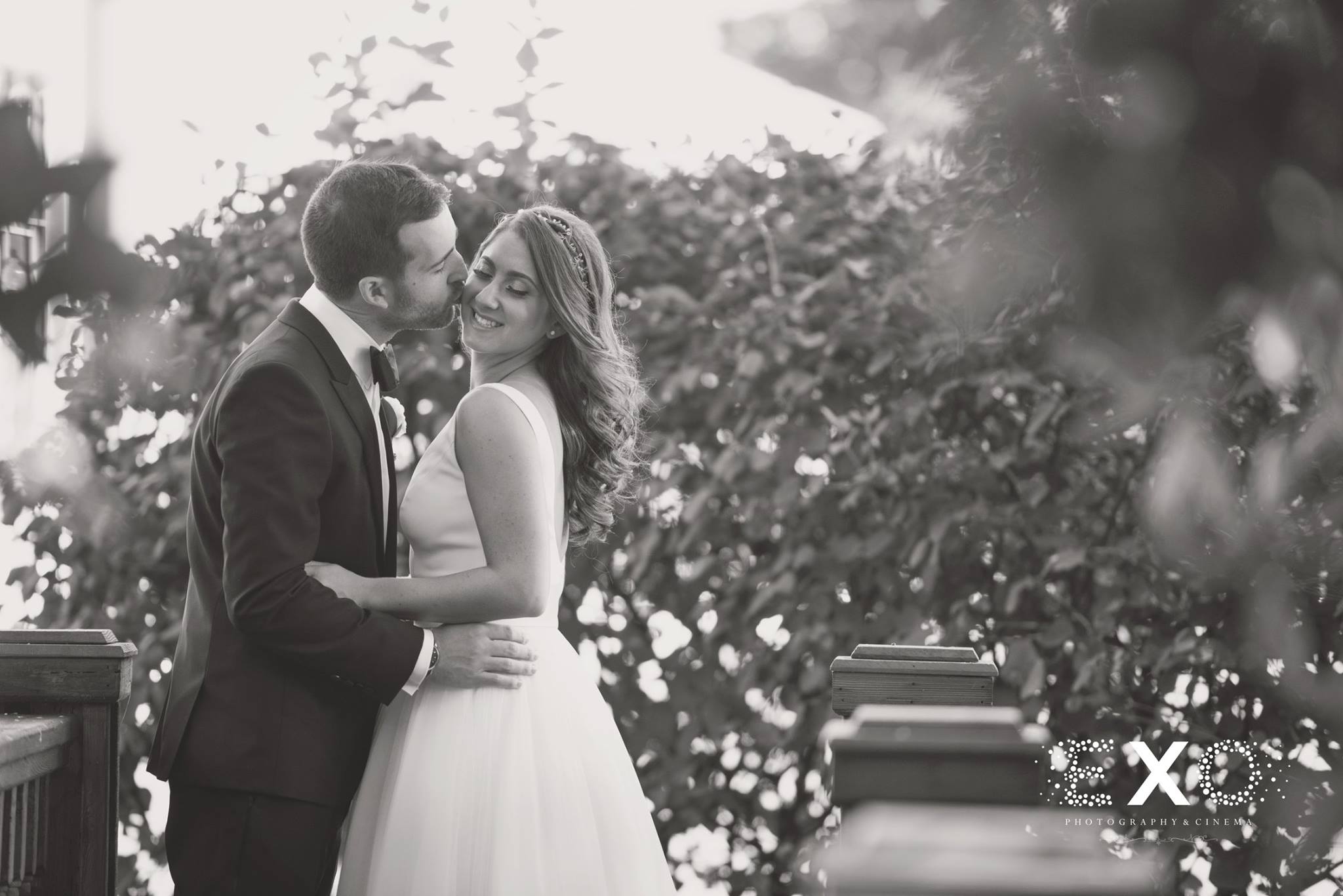black and white photo of groom kissing bride