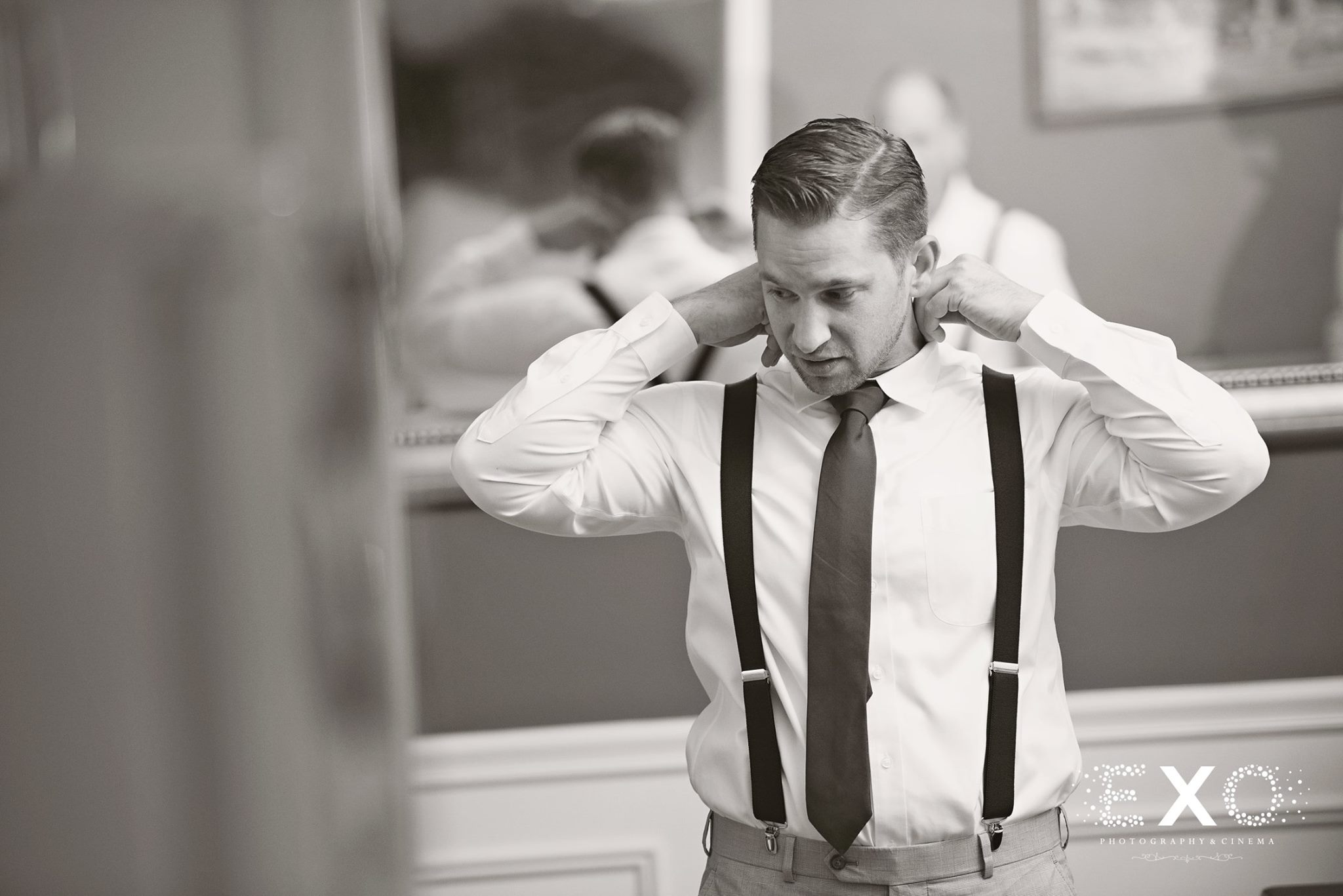black and white of groom getting dressed