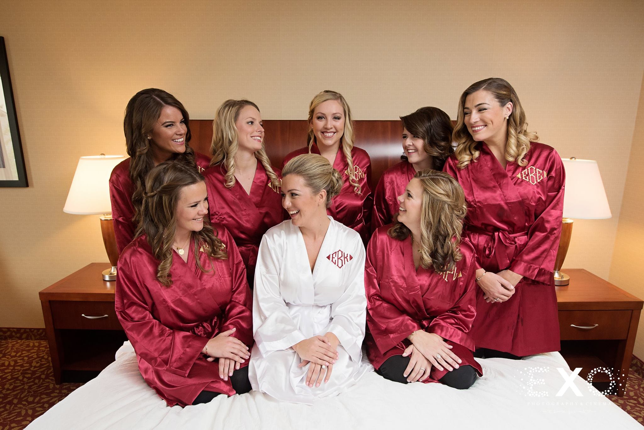 bride and bridesmaids on bed in robes