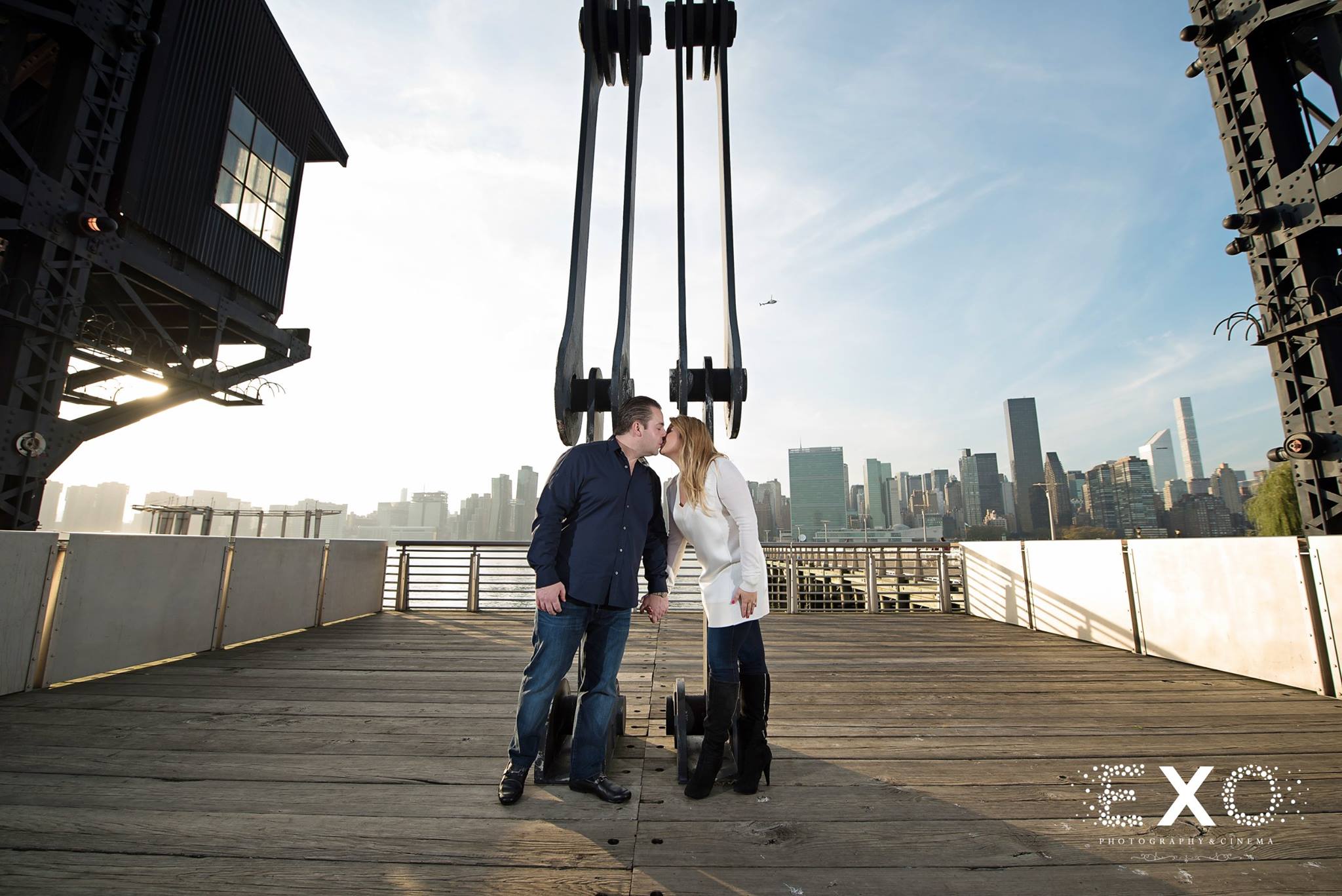 monica and lou kissing on boardwalk for their Gantry Park engagement session