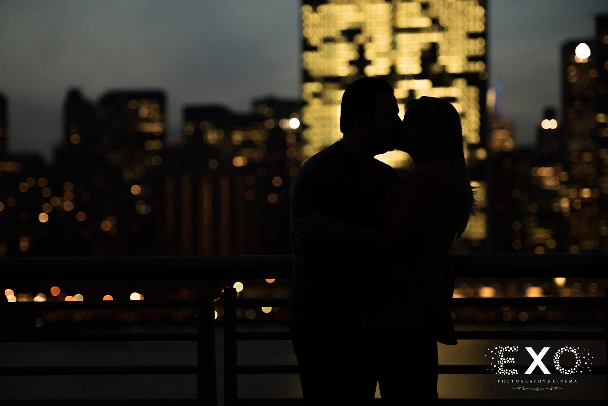 silhouette shot of couple kissing with nighttime skyline 