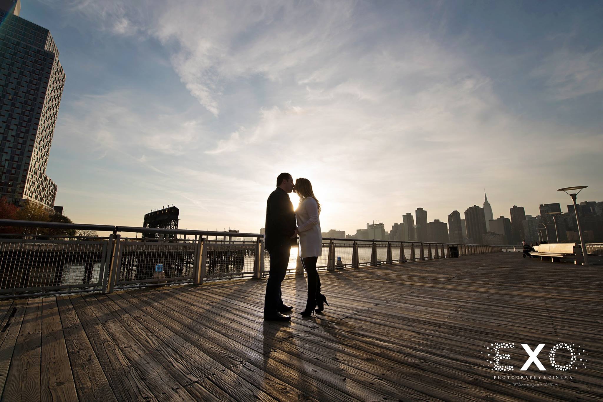 sunset shot of couple kissing on boardwalk 