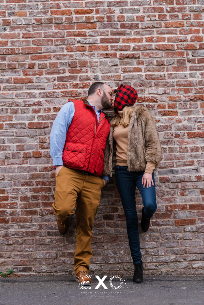 couple kissing in front of brick wall