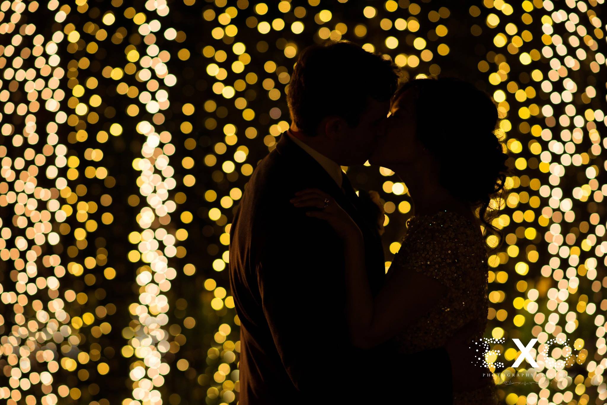 bride and groom kissing with string lights at Fox Hollow