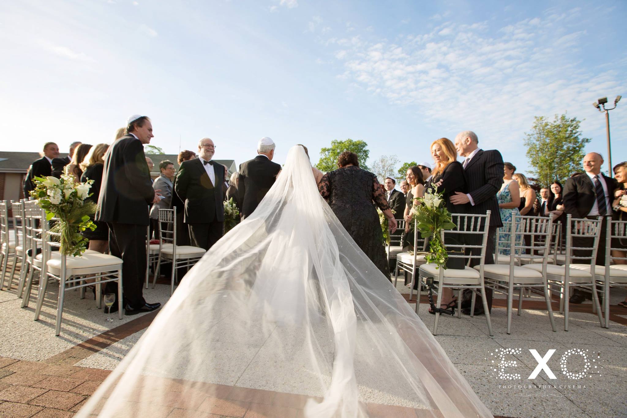 bride walking down the aisle with long veil from kleinfeld bridal
