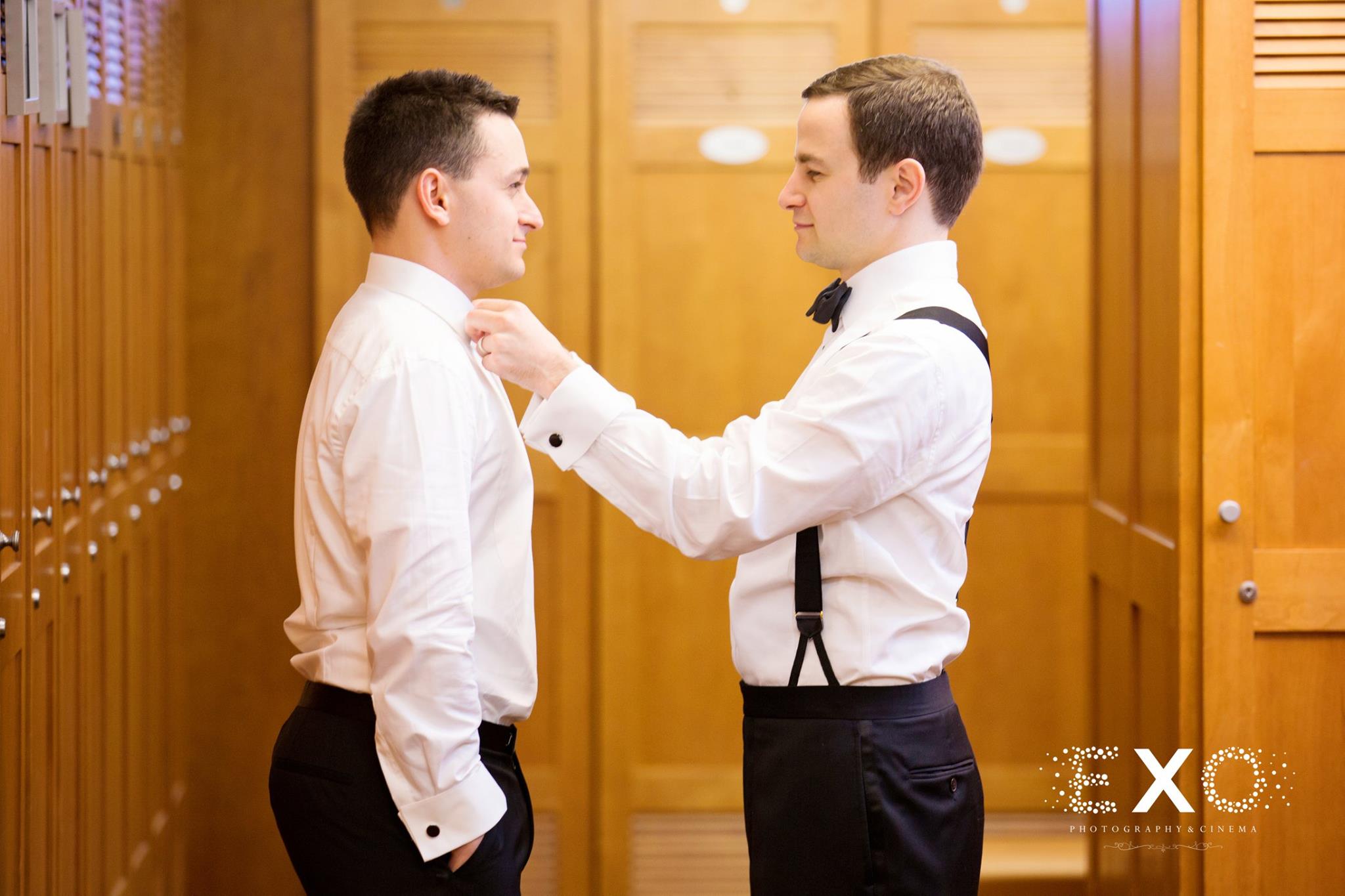 groomsmen helping groom with shirt