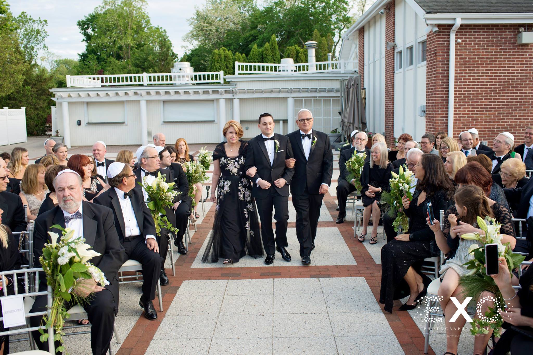 groom walking down aisle with parents at Engineers Country Club