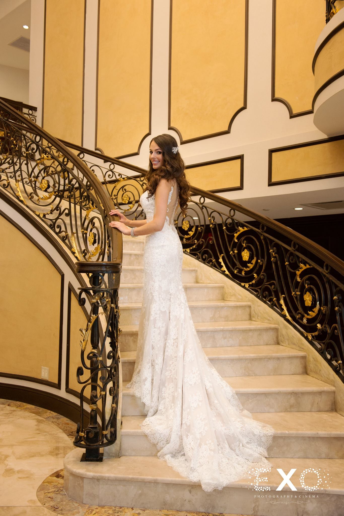 bride standing on stairs in castle couture gown designed by allure