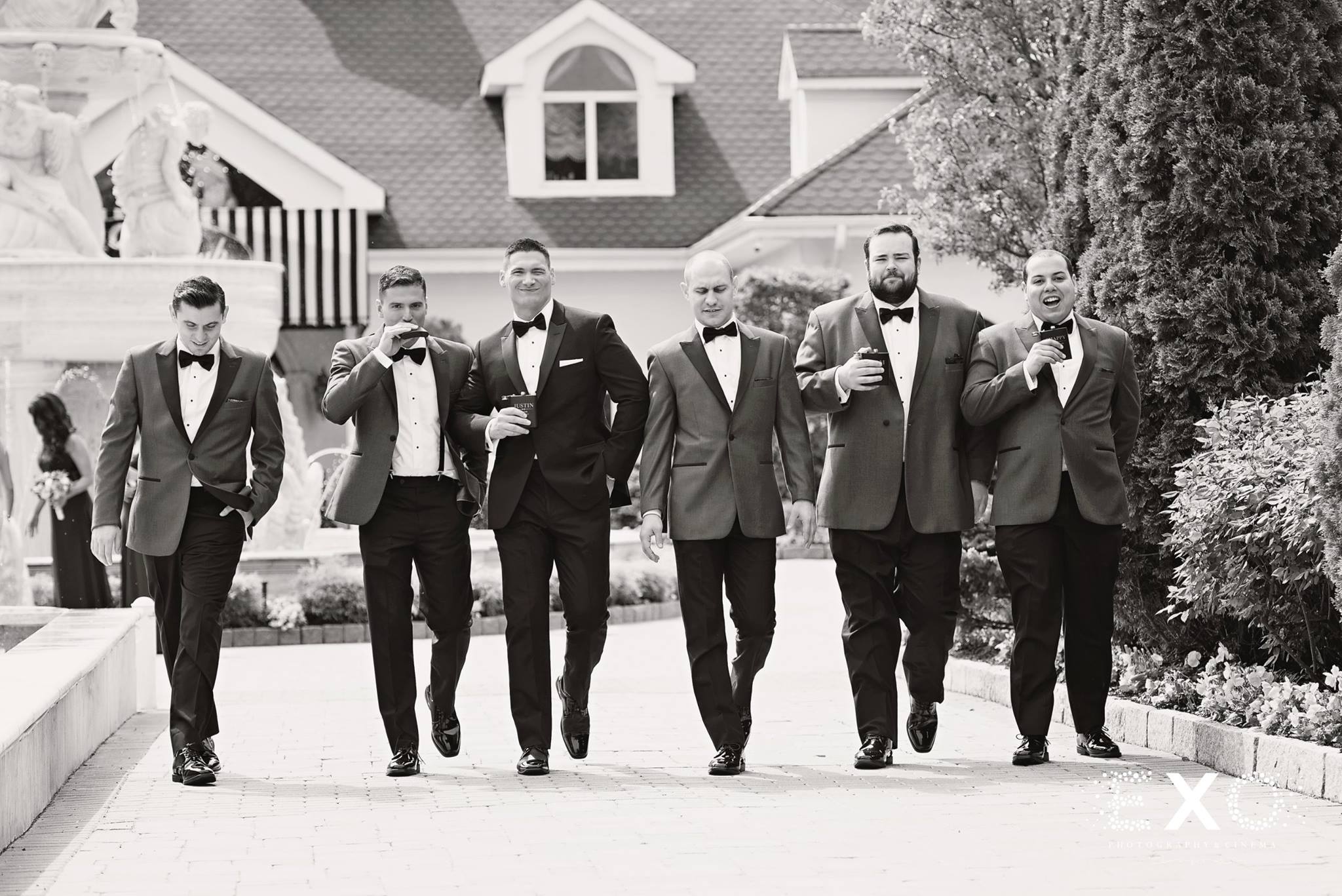 black and white image of groom and groomsmen walking 