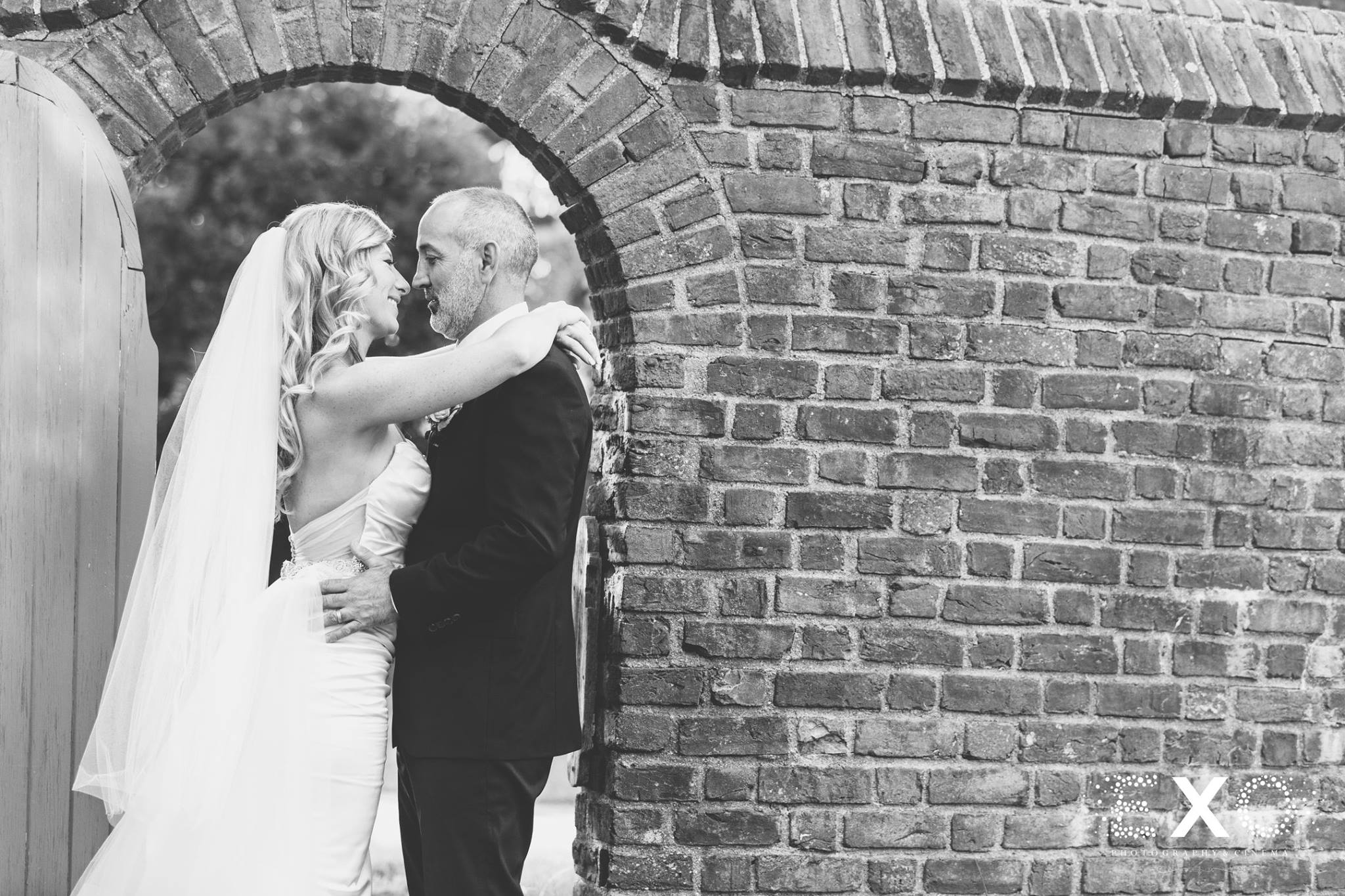 black and white image of bride and groom near brick wall