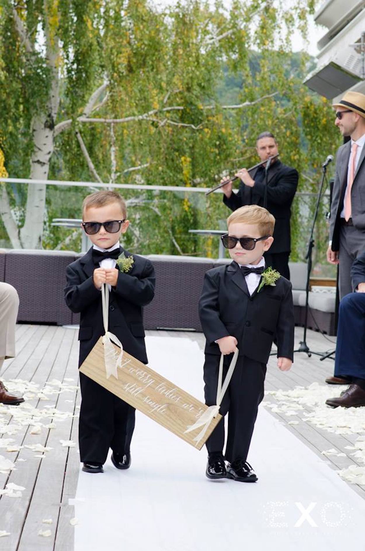 young boys walking down aisle with sign