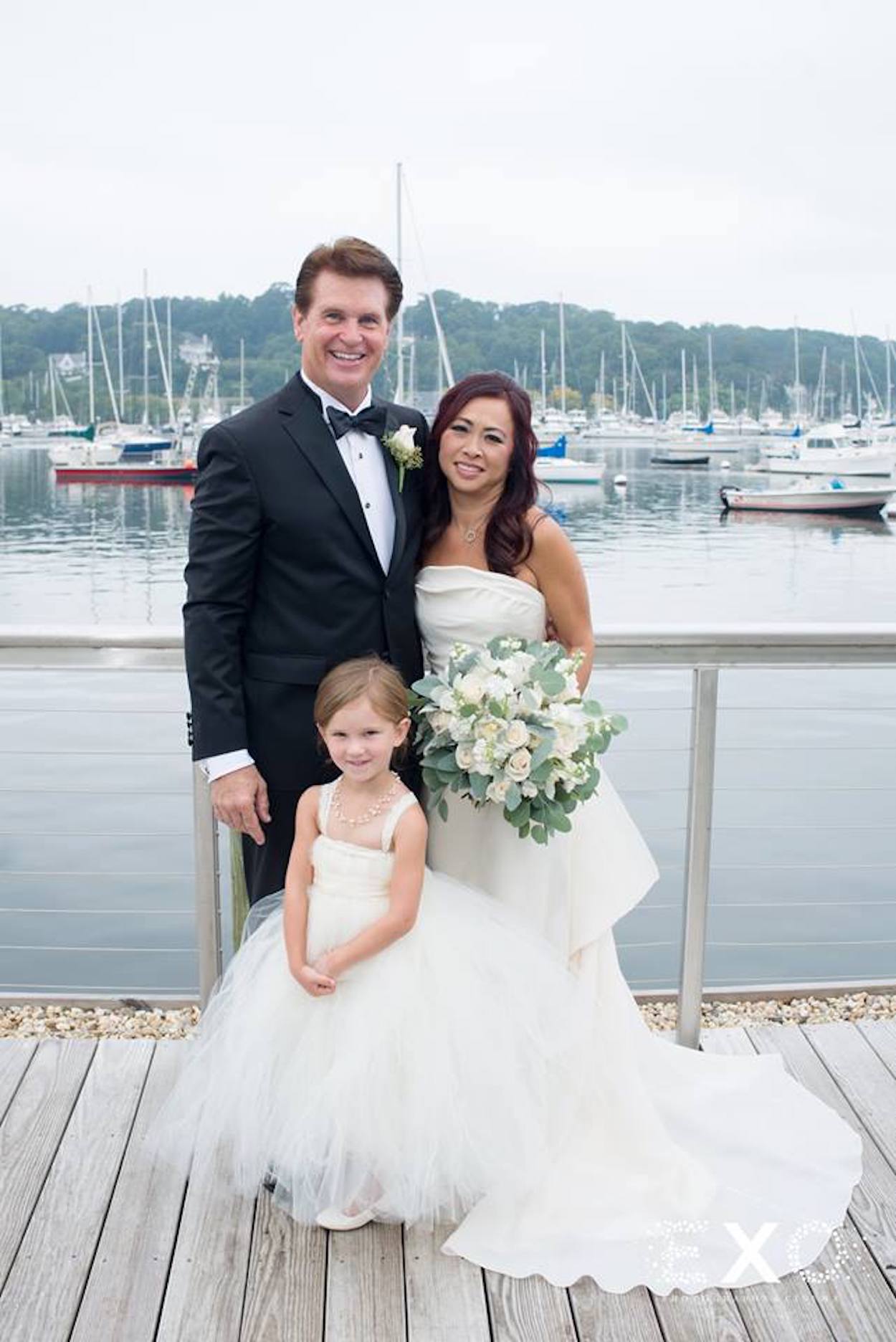 bride, groom, and flower girl on dock near harbor club at prime