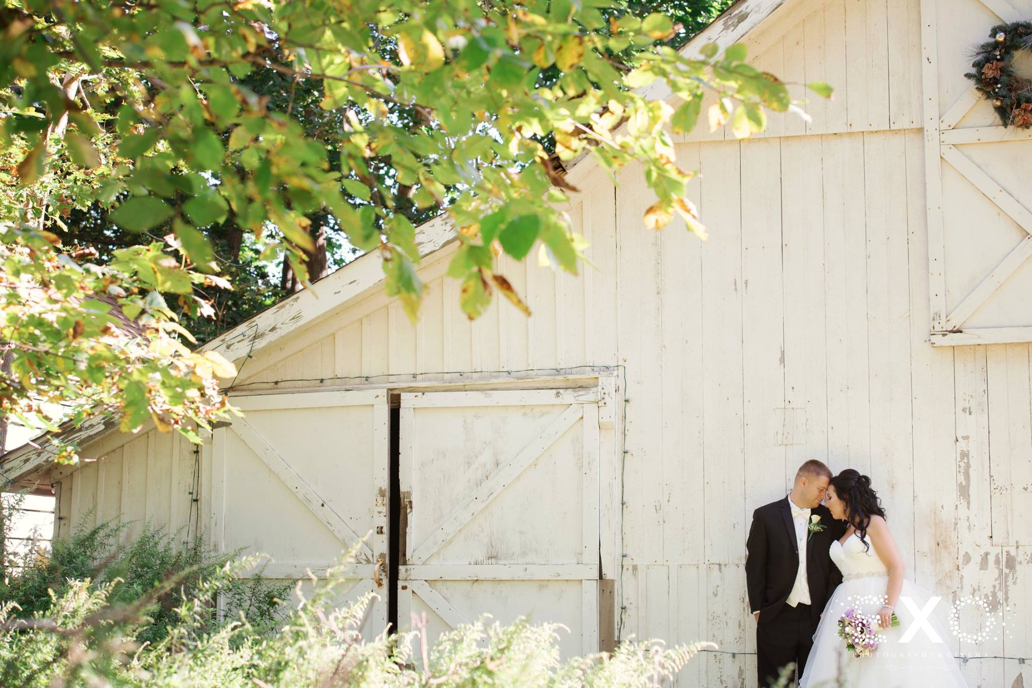 Bride and groom kissing near a white barn