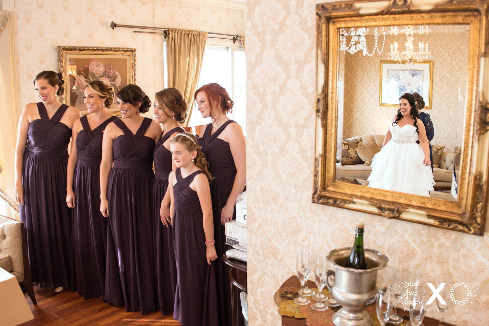 Mirror image of bride wearing burton bridals gown designed by stella york with bridesmaids