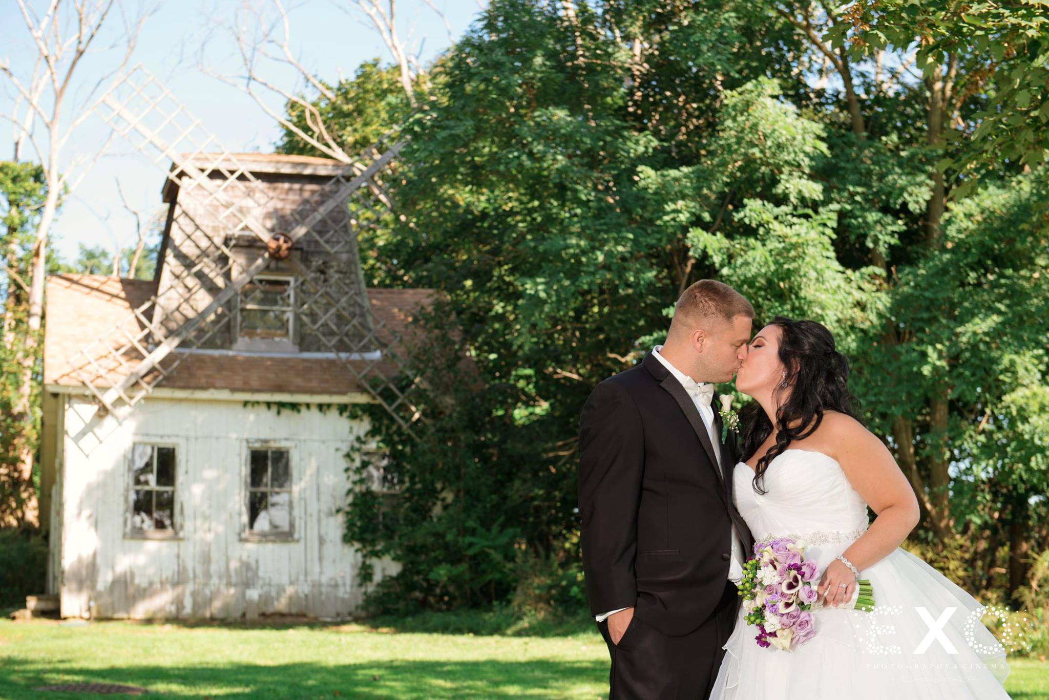 bride and groom kissing in front of old windmill