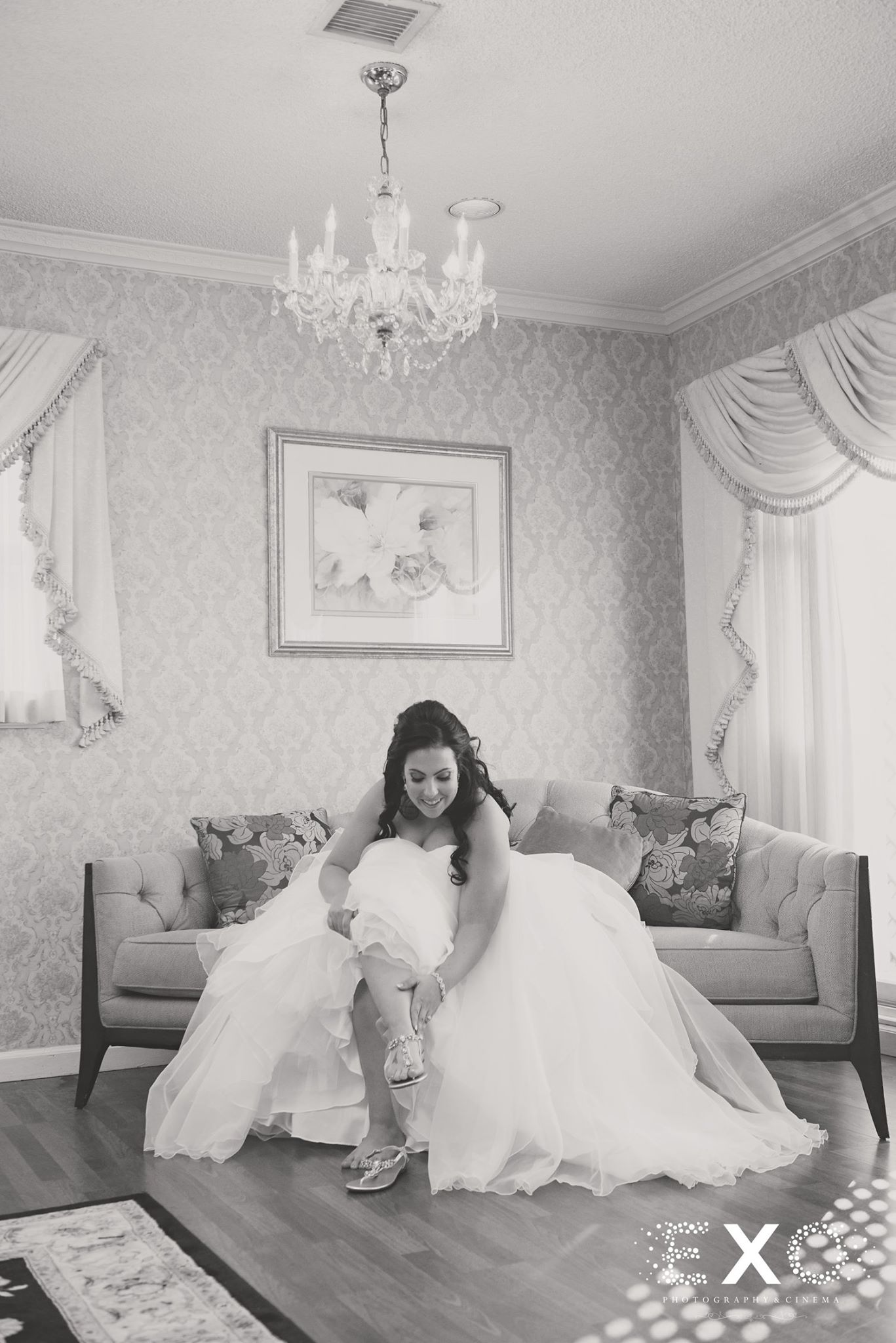 Black and white image of bride putting on Nina shoes for wedding ceremony