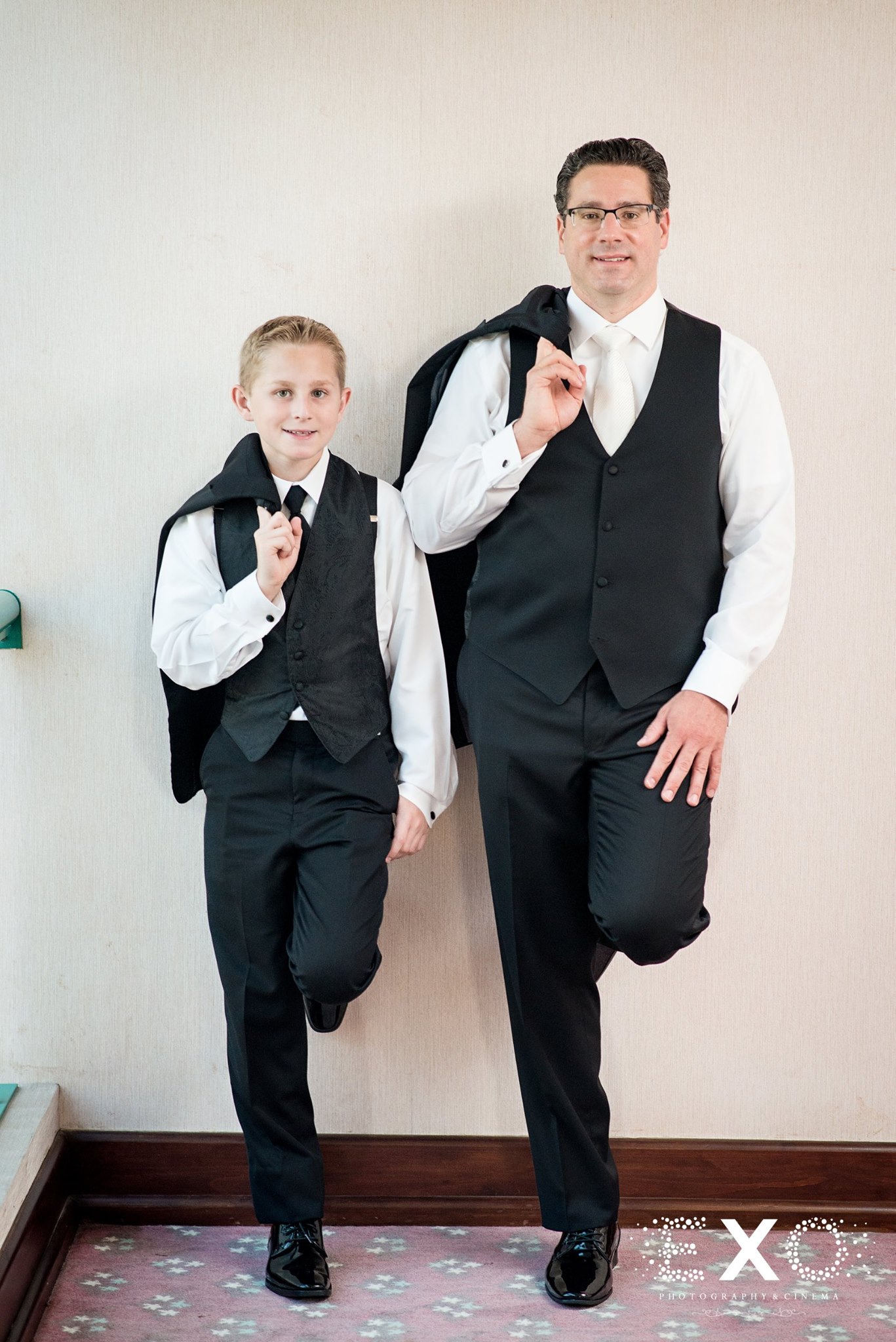 groom and young boy posed near a wall