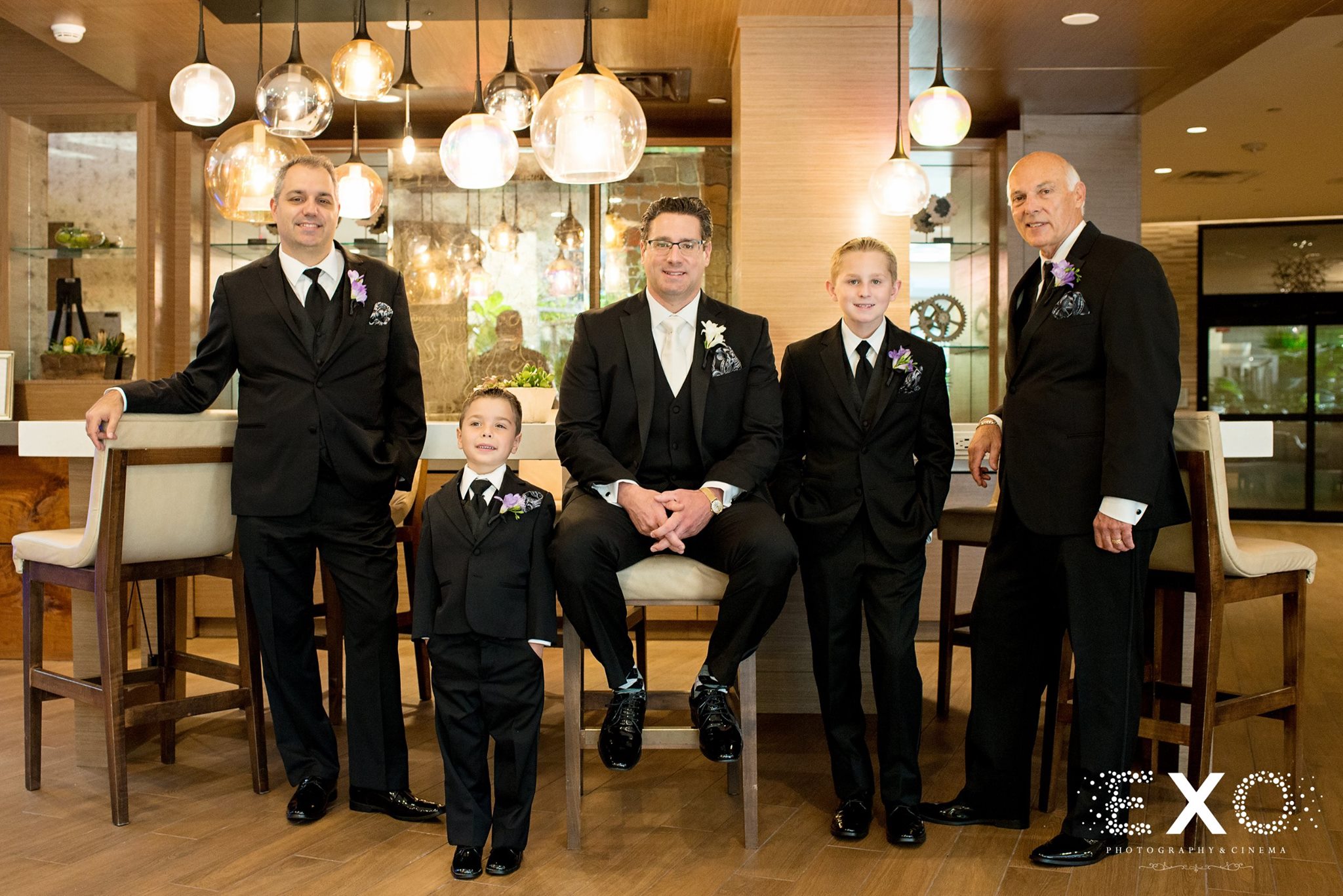 groom and men in chairs before harbor club at prime wedding