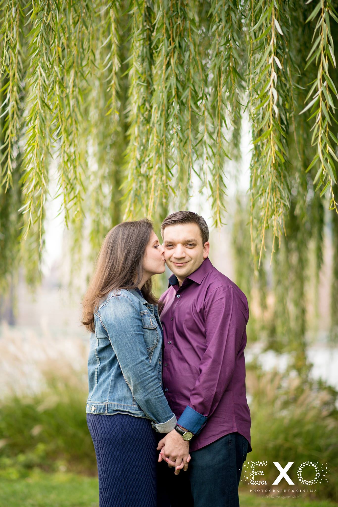 engaged couple kissing under willow tree at Gantry Park