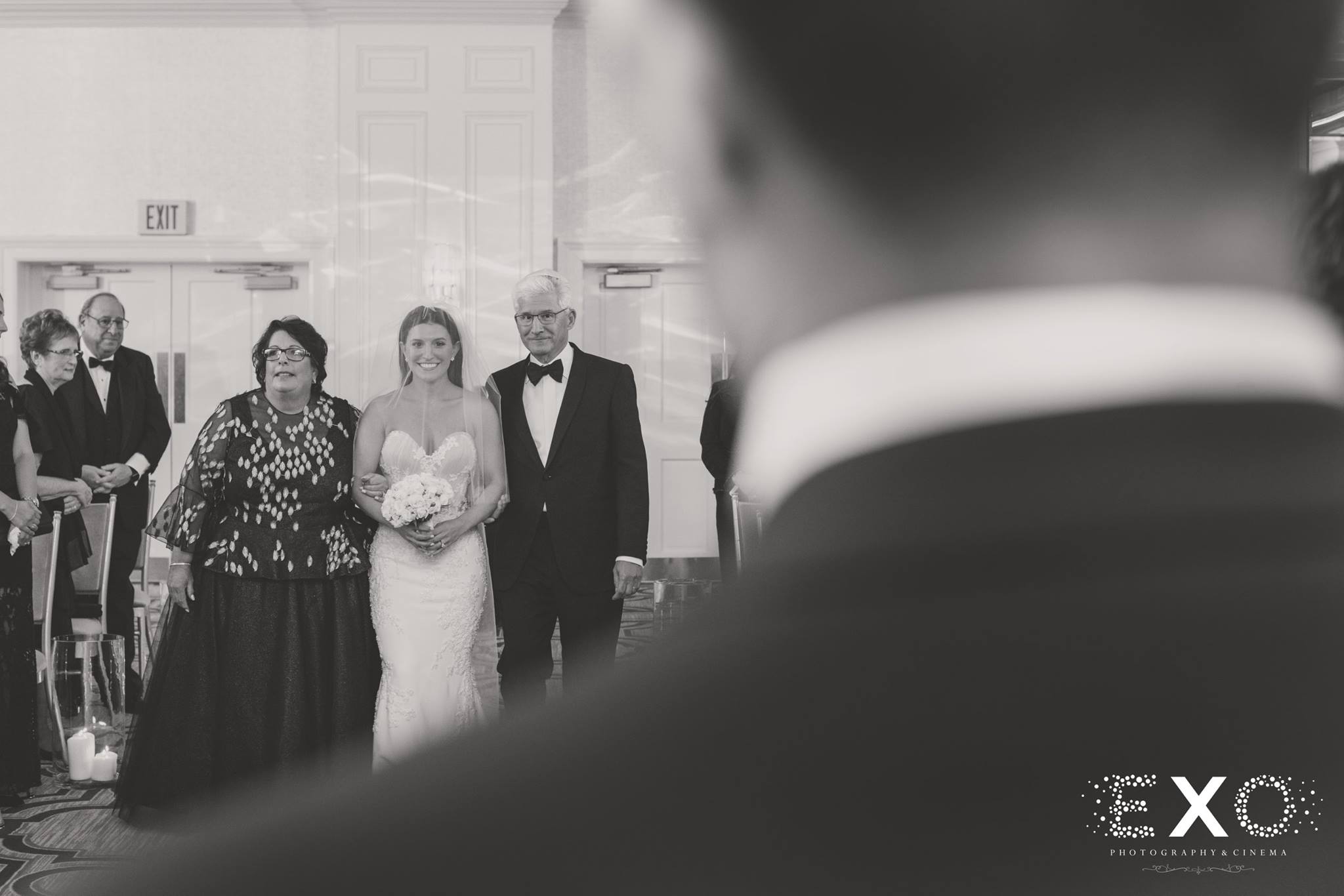 black and white image from grooms perspective of bride coming down aisle
