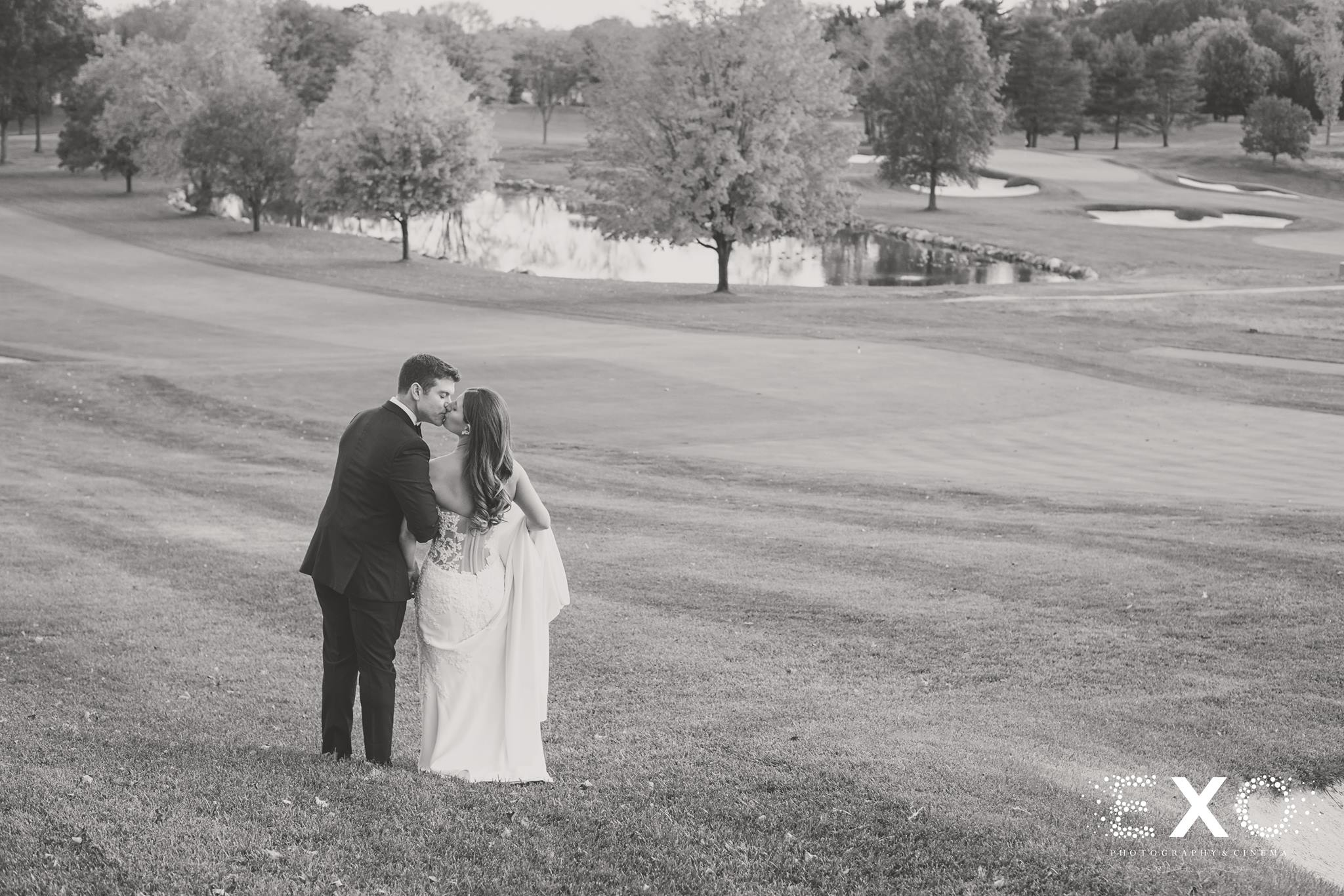 black and white photo of bride and groom kissing on Glen Head Country Club course