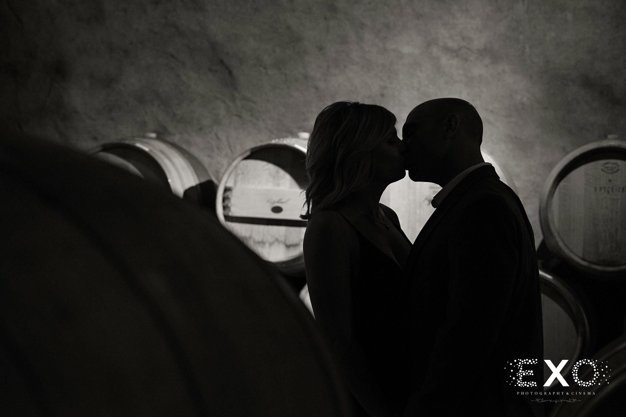 black and white shot of couple kissing in cellar at Raphael Vineyard