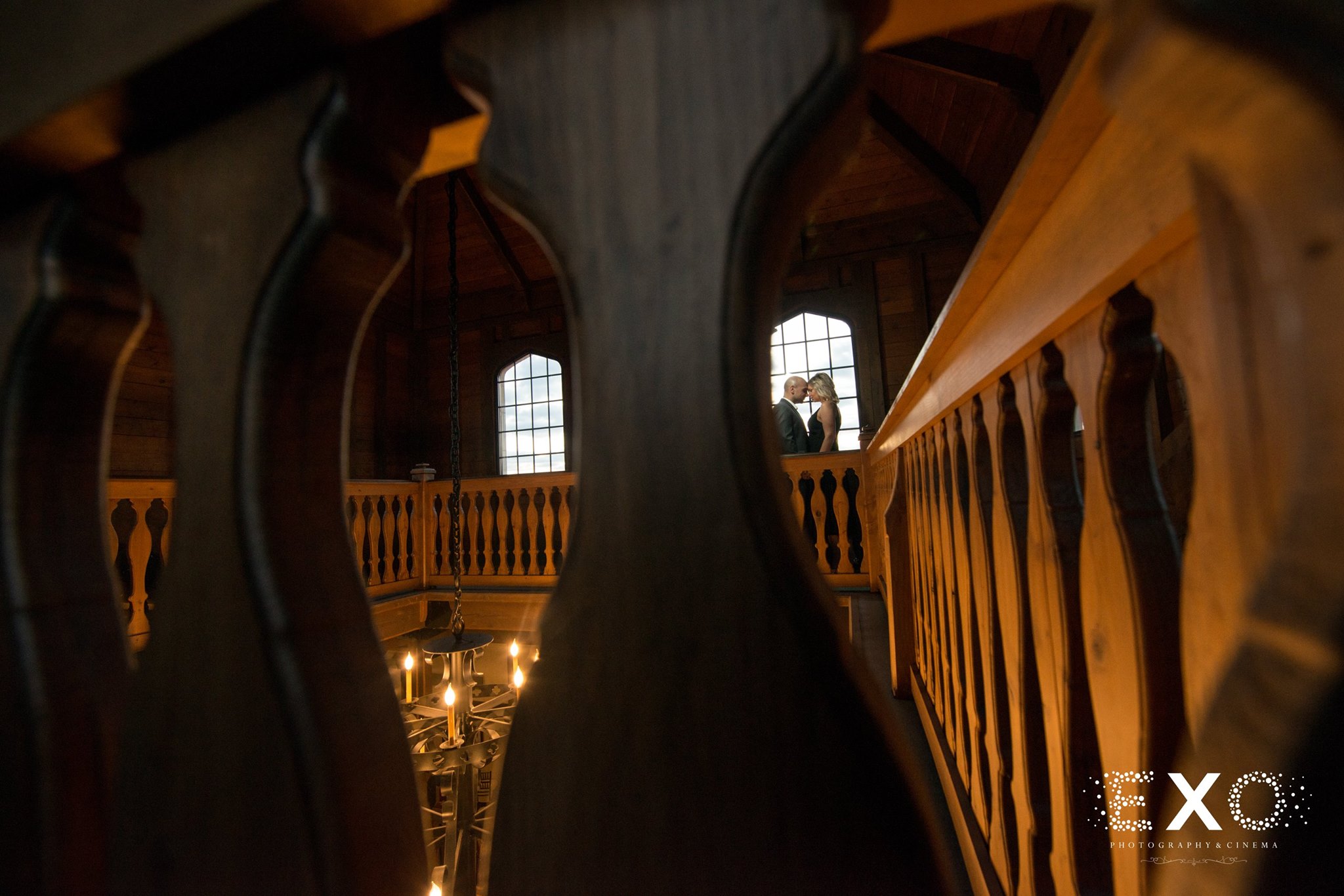 romantic image of couple through spaces of bannister at Raphael Vineyard