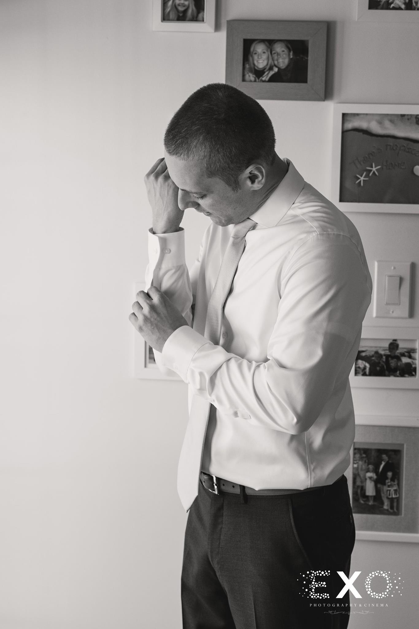 black and white image of groom adjusting shirt before Heritage Club at Bethpage wedding ceremony 