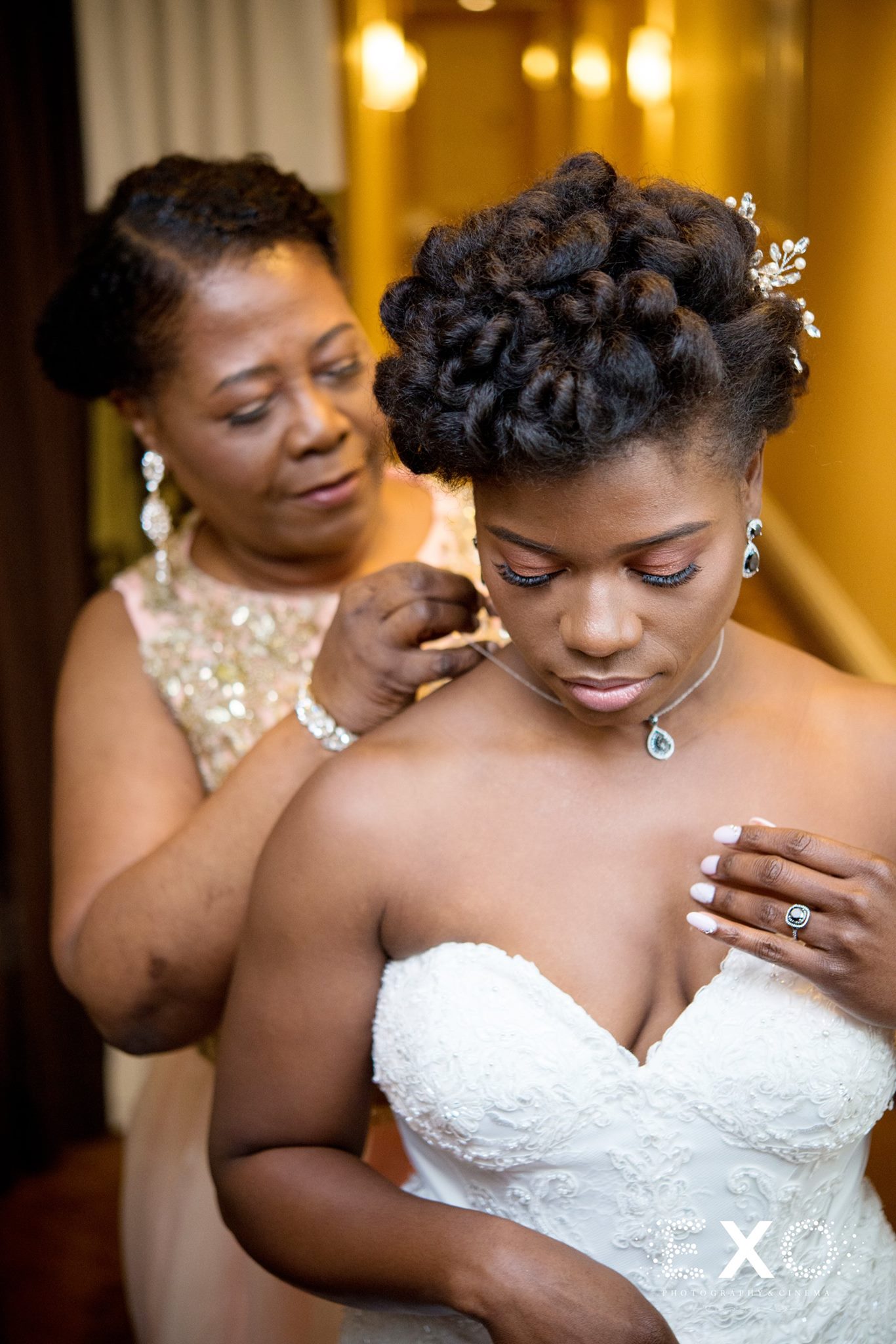 bridesmaid putting on brides jewelry 