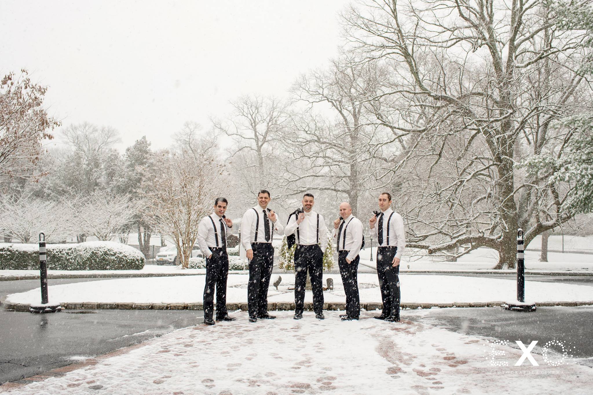 Groom and groomsmen standing in snow outside Royalton at Roslyn winter wedding venue
