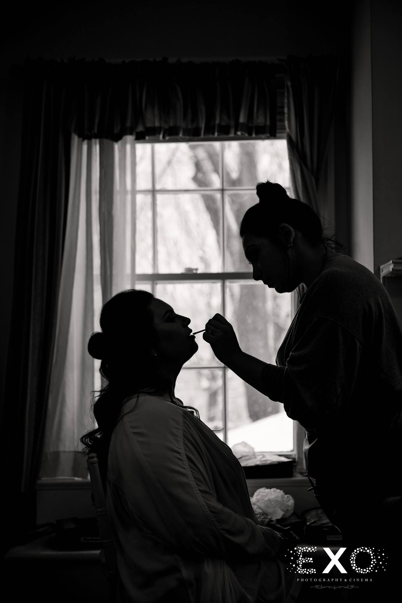 black and white silhouette shot of bride getting makeup done at Royalton at Roslyn mansion