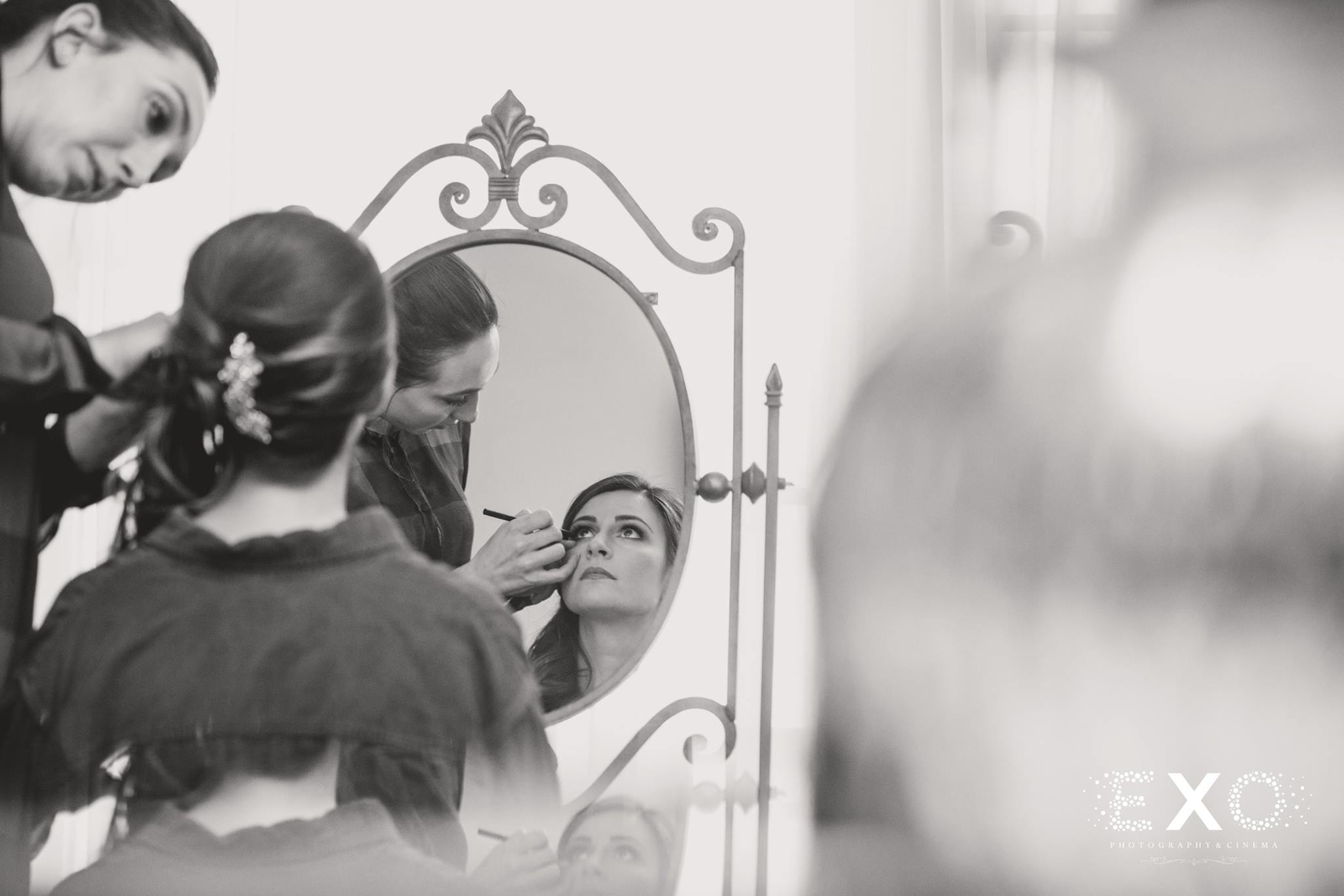 black and white image of bride getting makeup done by Bridget Grover