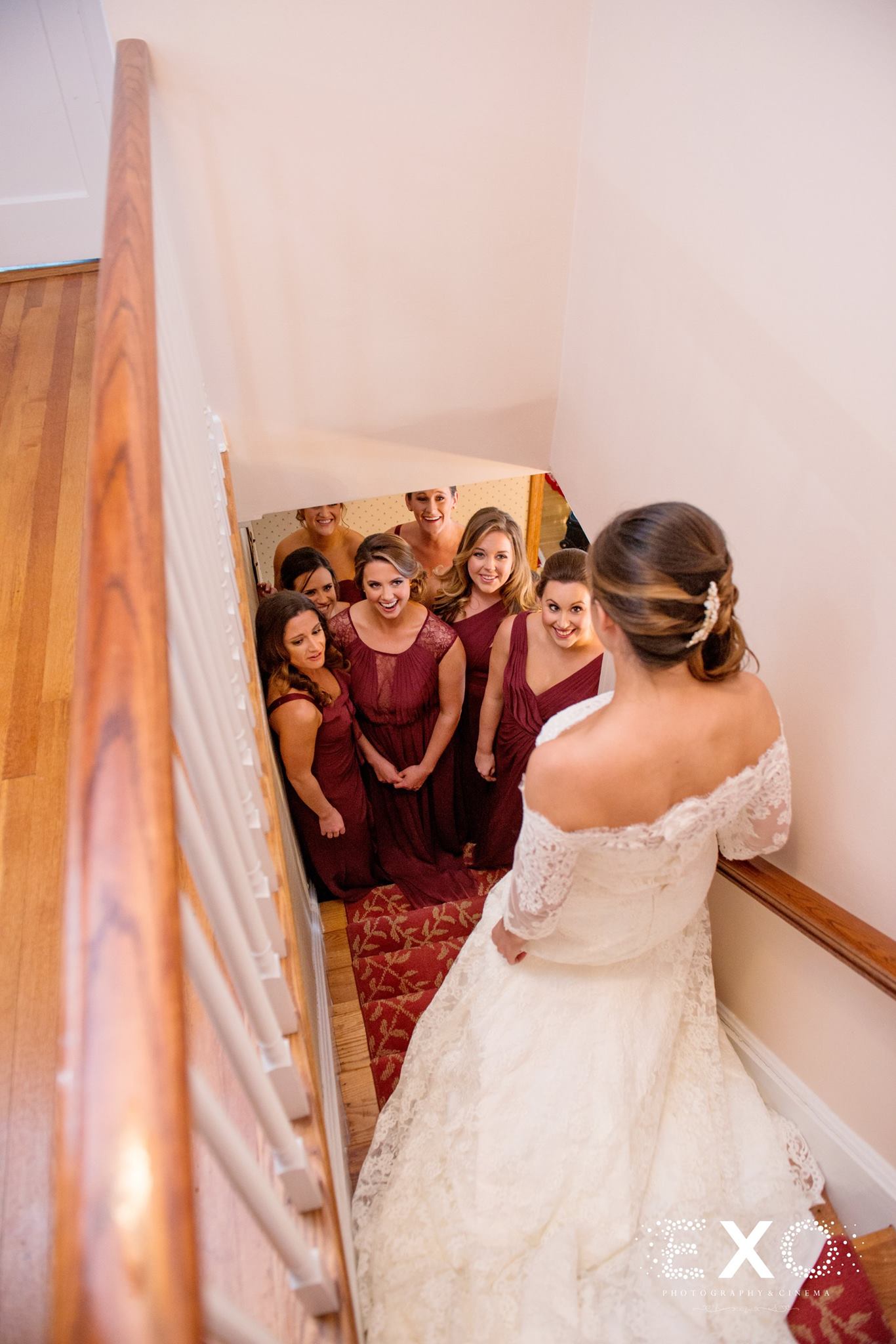 bride going down steps in Kleinfeld Bridal gown toward bridesmaids